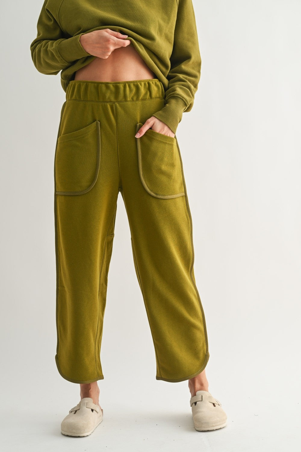 lounge pants with relaxed cropped fit, curved hem, oversized front bucket patch pockets, elastic waistband, seam detailing along sides, athleisure