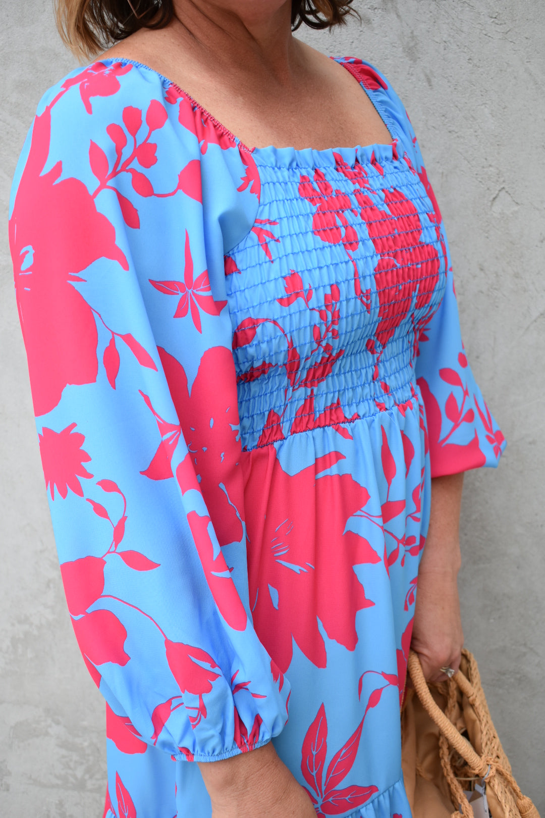 Bright blue and fuchsia floral print babydoll mini dress with smocked bodice, ruffle hem, 3/4th length balloon sleeves, square neckline. The brand is First Love.