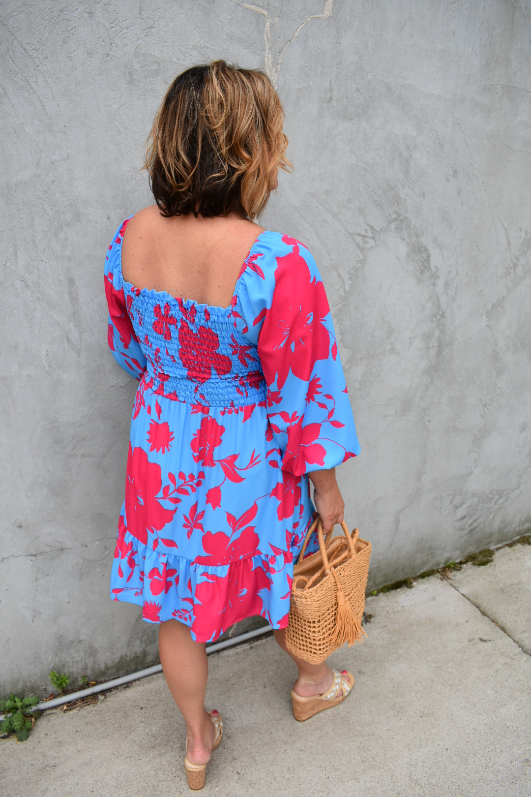 Bright blue and fuchsia floral print babydoll mini dress with smocked bodice, ruffle hem, 3/4th length balloon sleeves, square neckline. The brand is First Love.