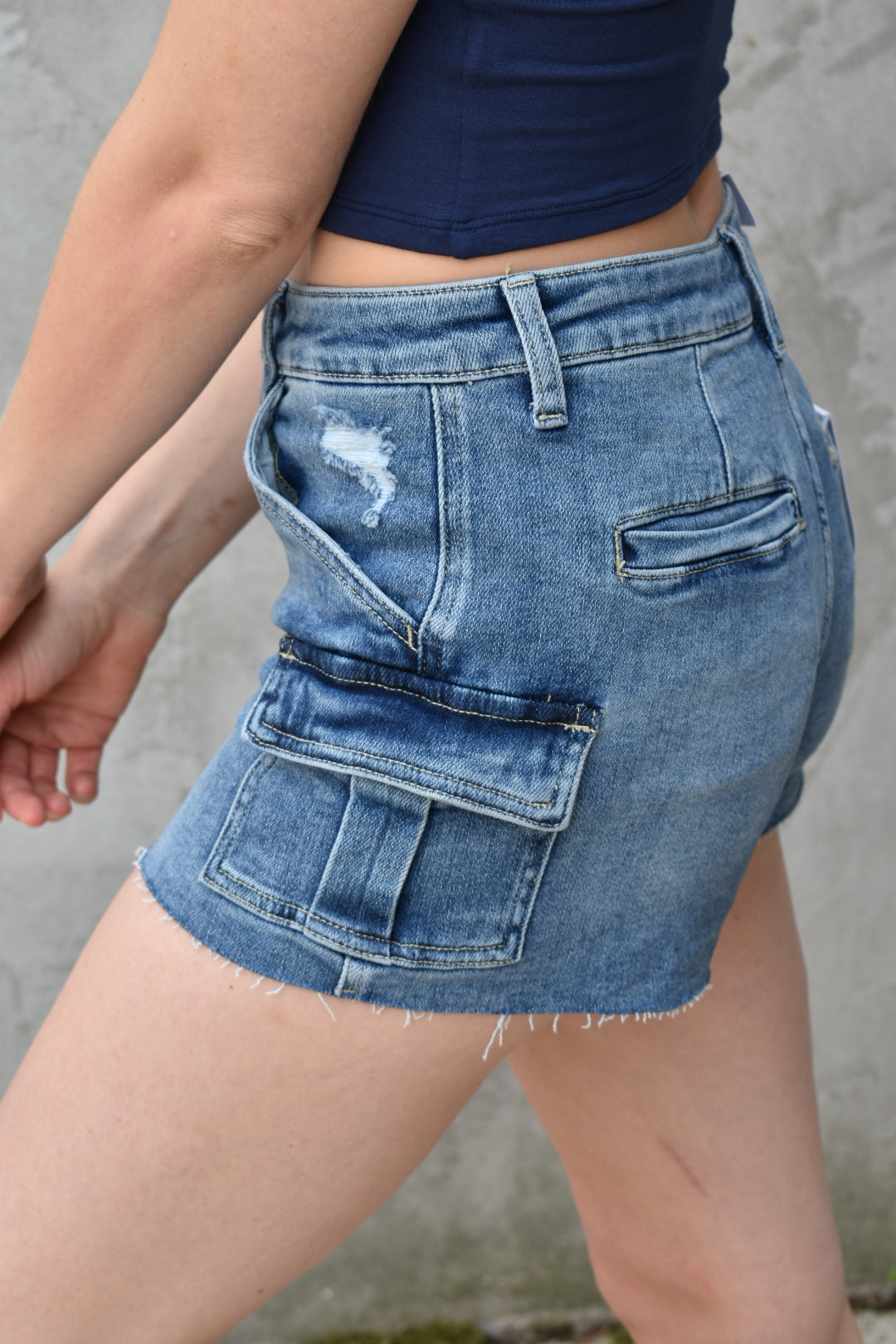 denim high rise medium wash cargo shorts with small cargo style pockets on the side. Stretch denim. The brand is Vervet