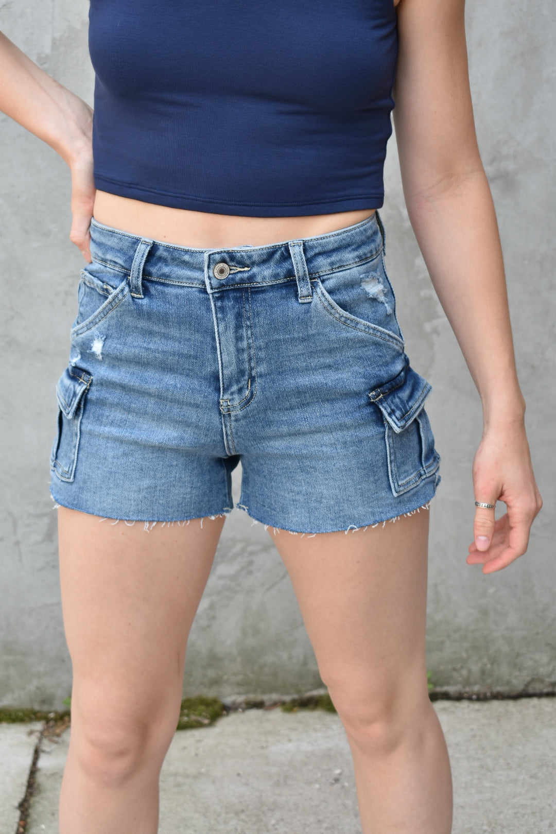 denim high rise medium wash cargo shorts with small cargo style pockets on the side. Stretch denim. The brand is Vervet