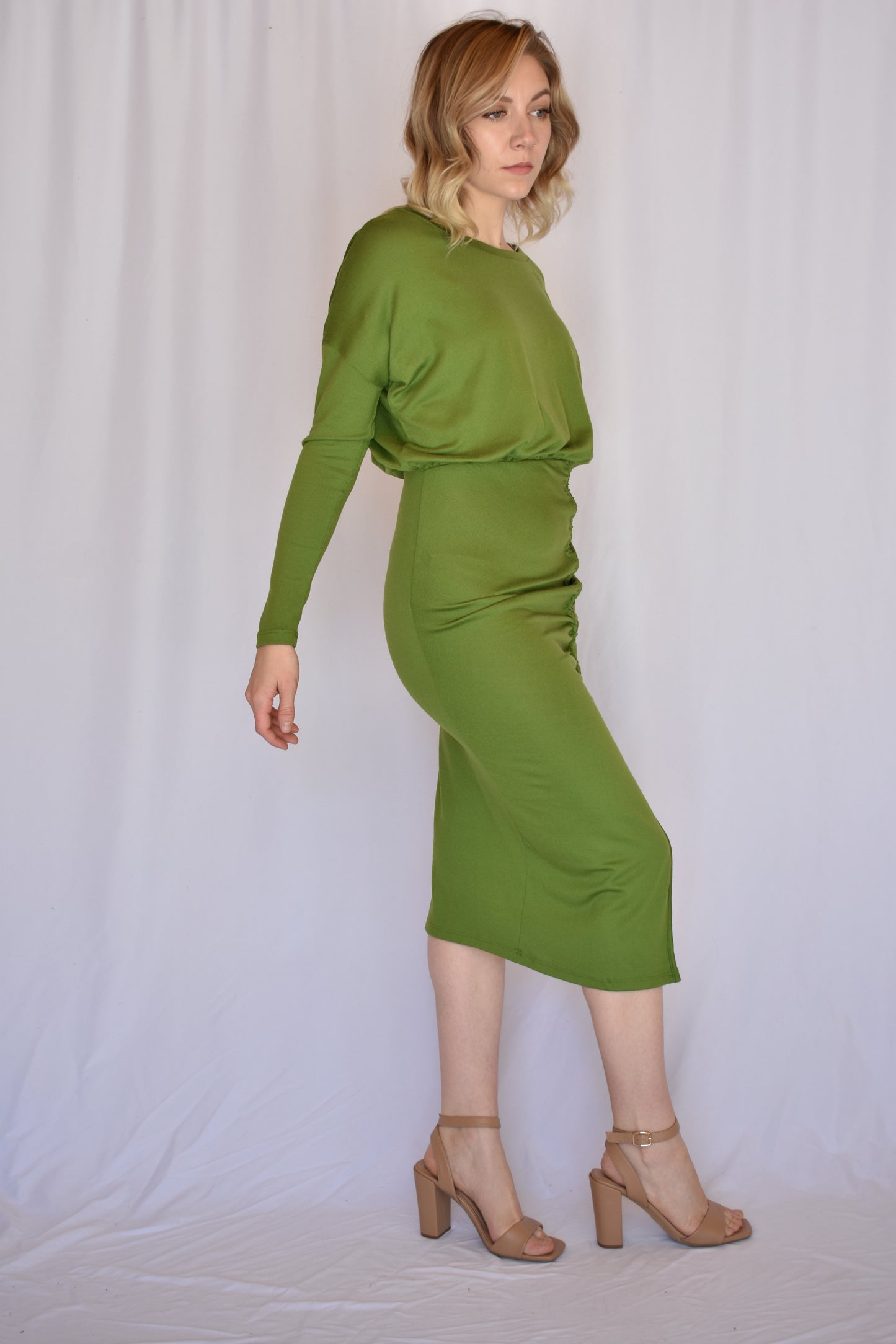 long sleeve avocado green midi dress with boat neck and relaxed bodice that transitions into a bodycon fit with synching drawstring that goes into a side slit.