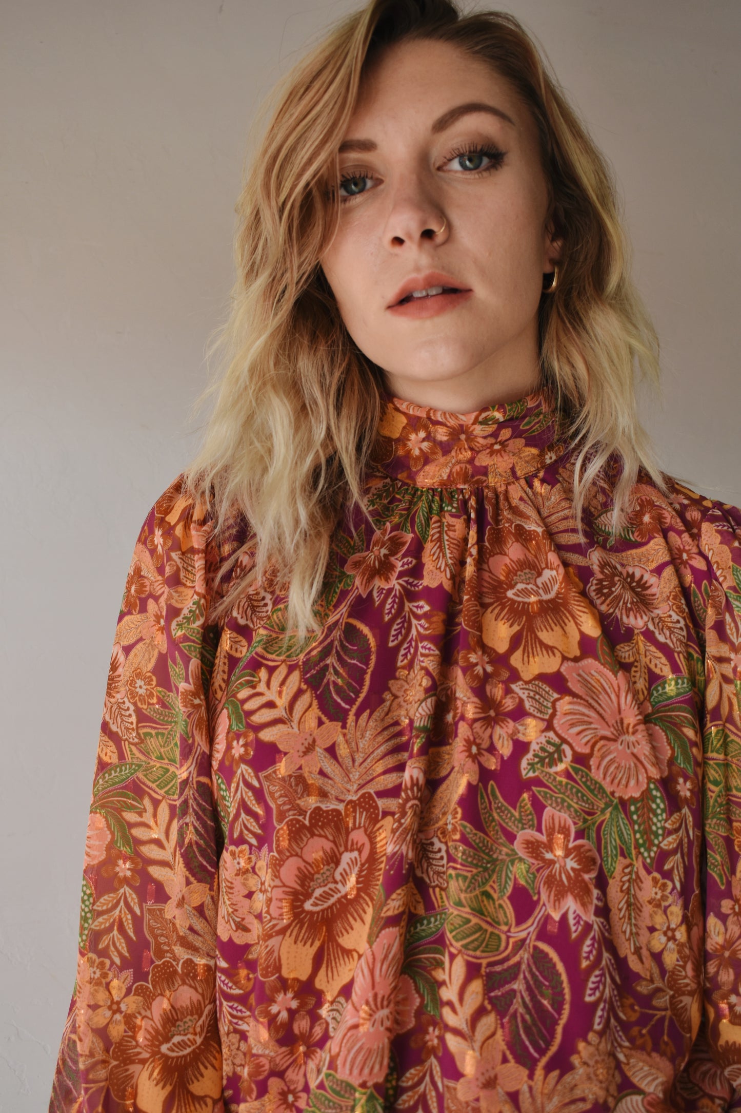 burgundy, green, terracotta (and hits of metallic gold thread) color scheme floral patterned blouse with high neckline, long balloon sleeve with smocked cuff, and back neck button closure. flowy fit and full length
