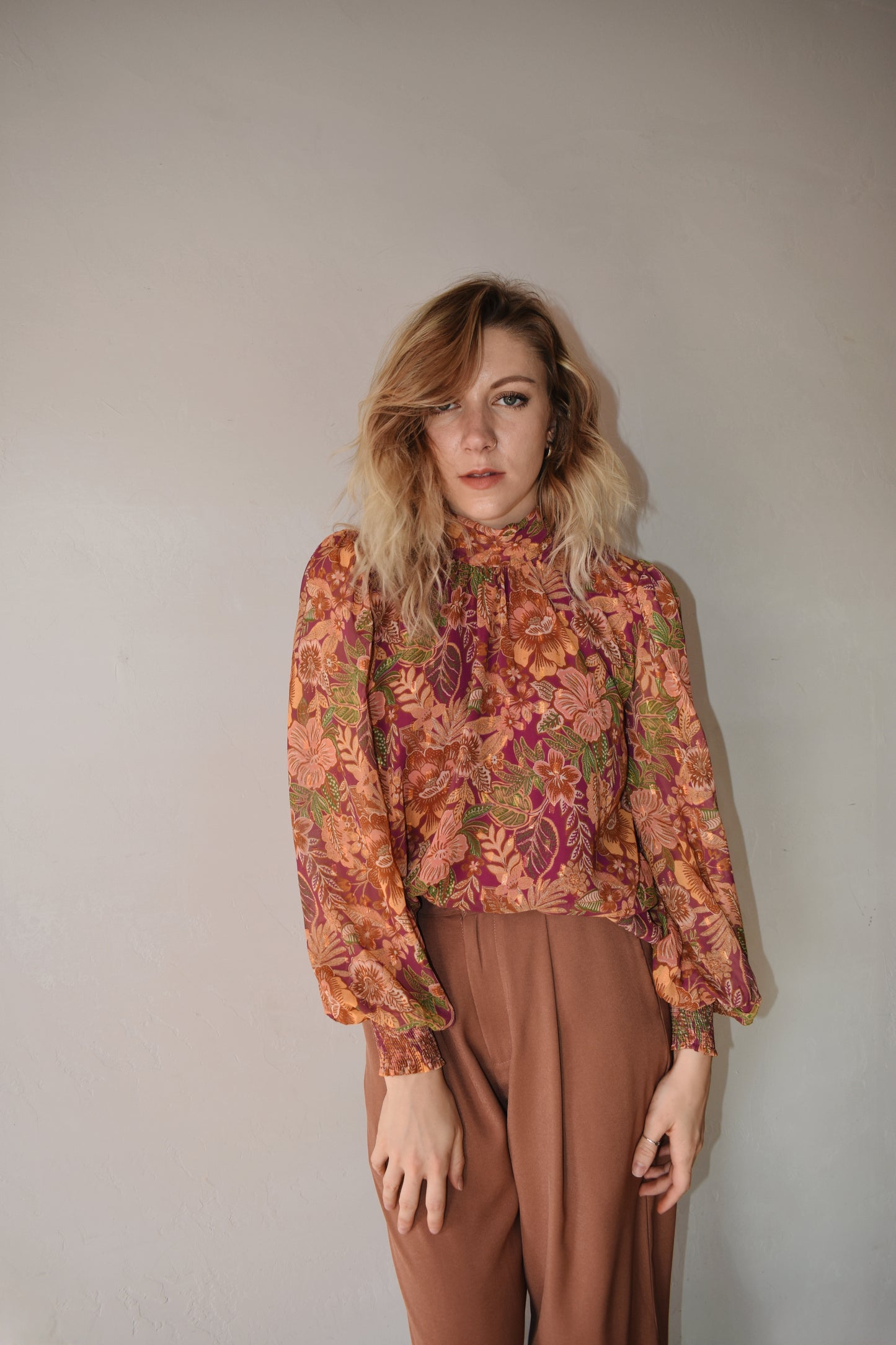 burgundy, green, terracotta (and hits of metallic gold thread) color scheme floral patterned blouse with high neckline, long balloon sleeve with smocked cuff, and back neck button closure. flowy fit and full length
