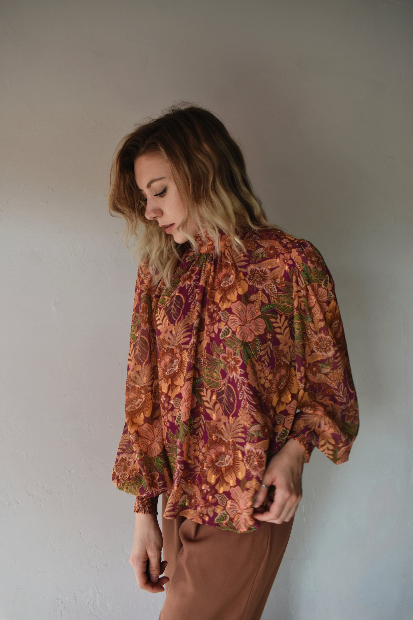 burgundy, green, terracotta (and hits of metallic gold thread) color scheme floral patterned blouse with high neckline, long balloon sleeve with smocked cuff, and back neck button closure. flowy fit and full length