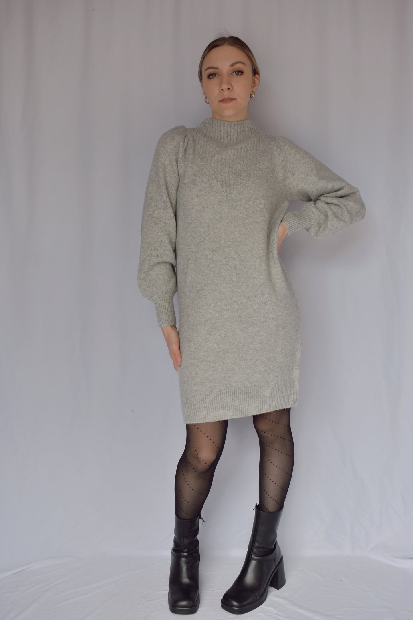 heather gray sweater dress with long sleeves. ribbed cuffs and mock neck with v neck ribbed detail. slight puff on shoulders. hits just above the knees. relaxed fit, not oversized.
