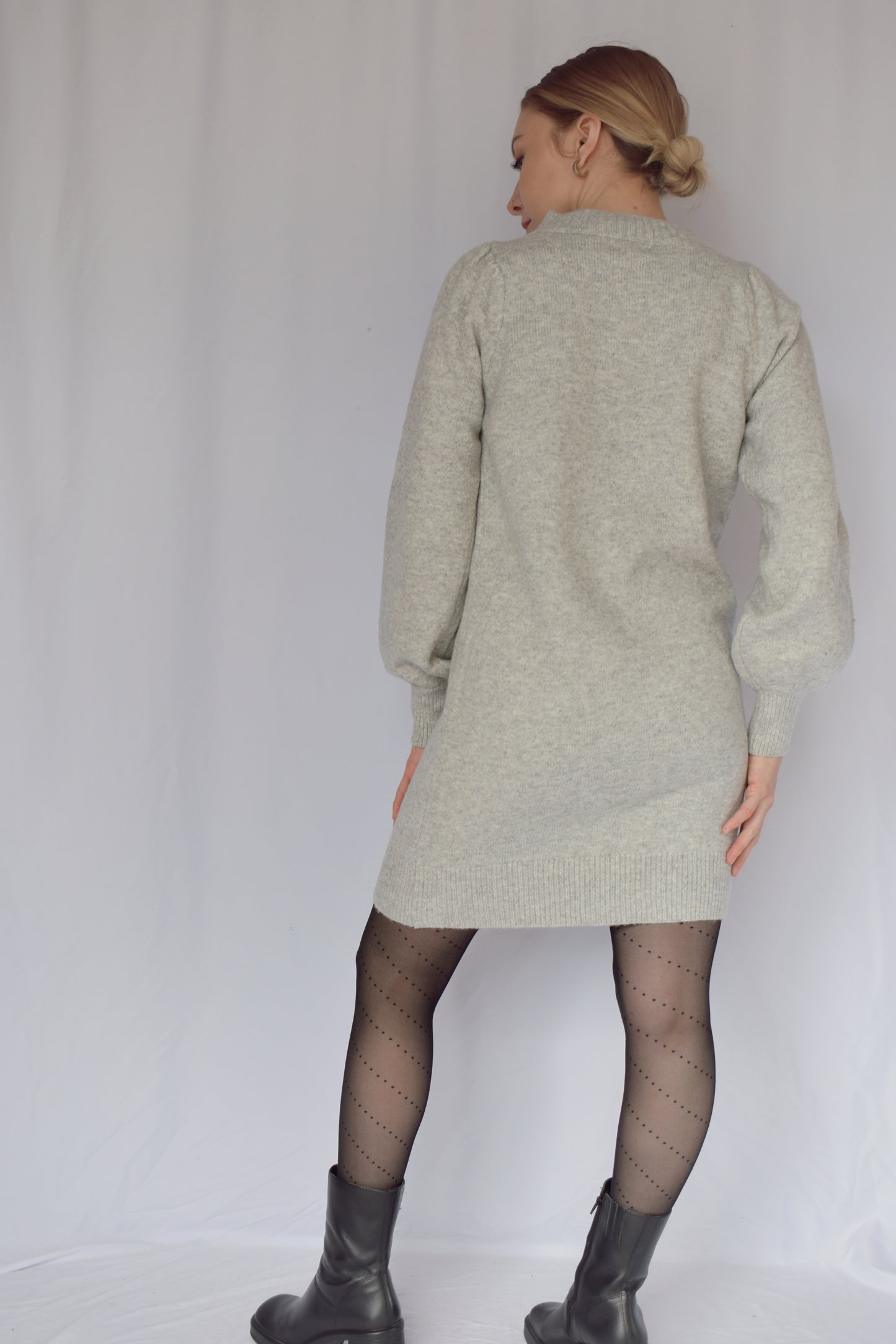 heather gray sweater dress with long sleeves. ribbed cuffs and mock neck with v neck ribbed detail. slight puff on shoulders. hits just above the knees. relaxed fit, not oversized.