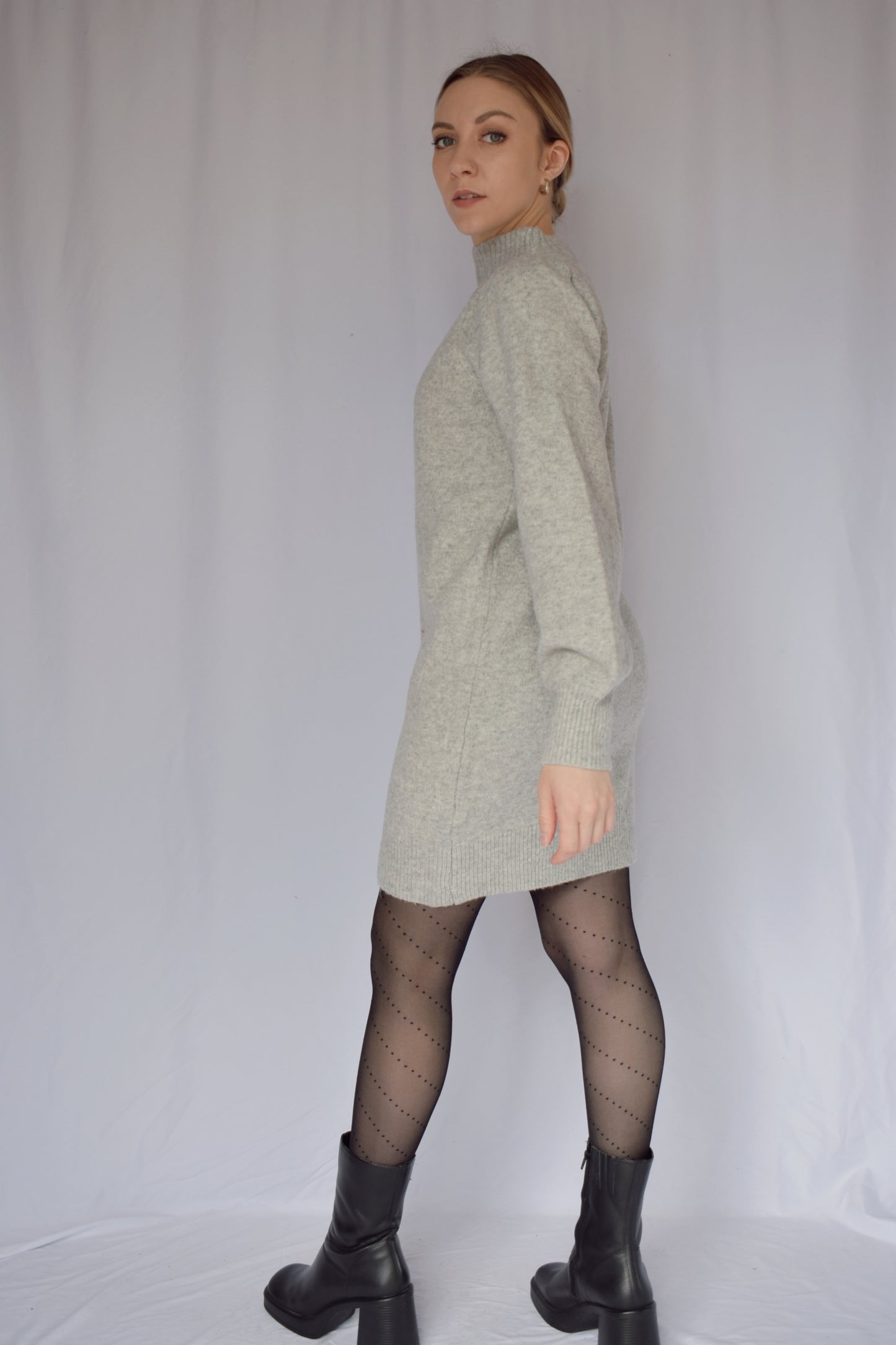 heather gray sweater dress with long sleeves. ribbed cuffs and mock neck with v neck ribbed detail. slight puff on shoulders. hits just above the knees. relaxed fit, not oversized.