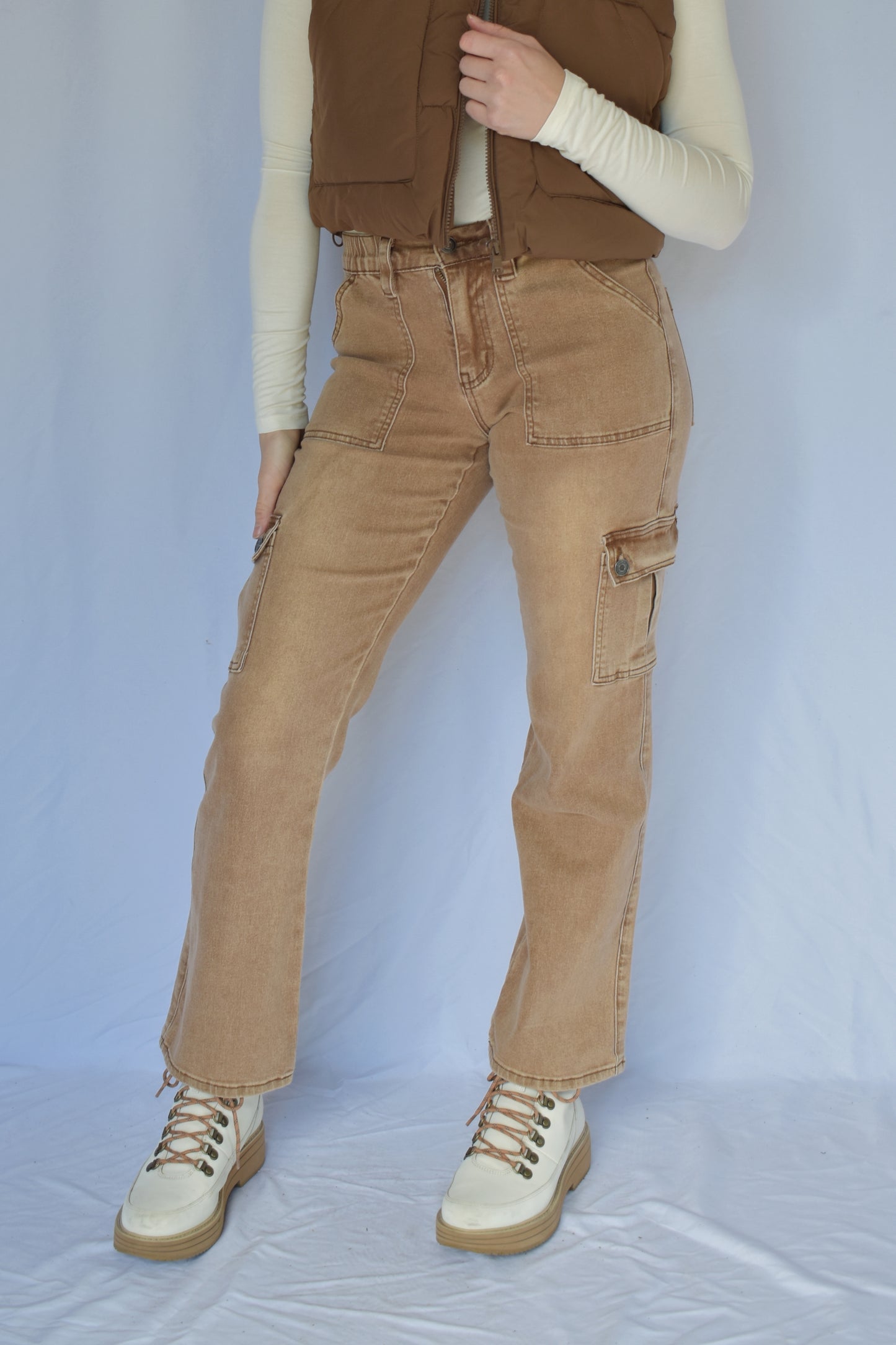 Tan stretch cargo jeans with side pockets with button enclosure and front patch pockets. also pockets on the back. elastic waist. straight leg. mid rise. belt loops.