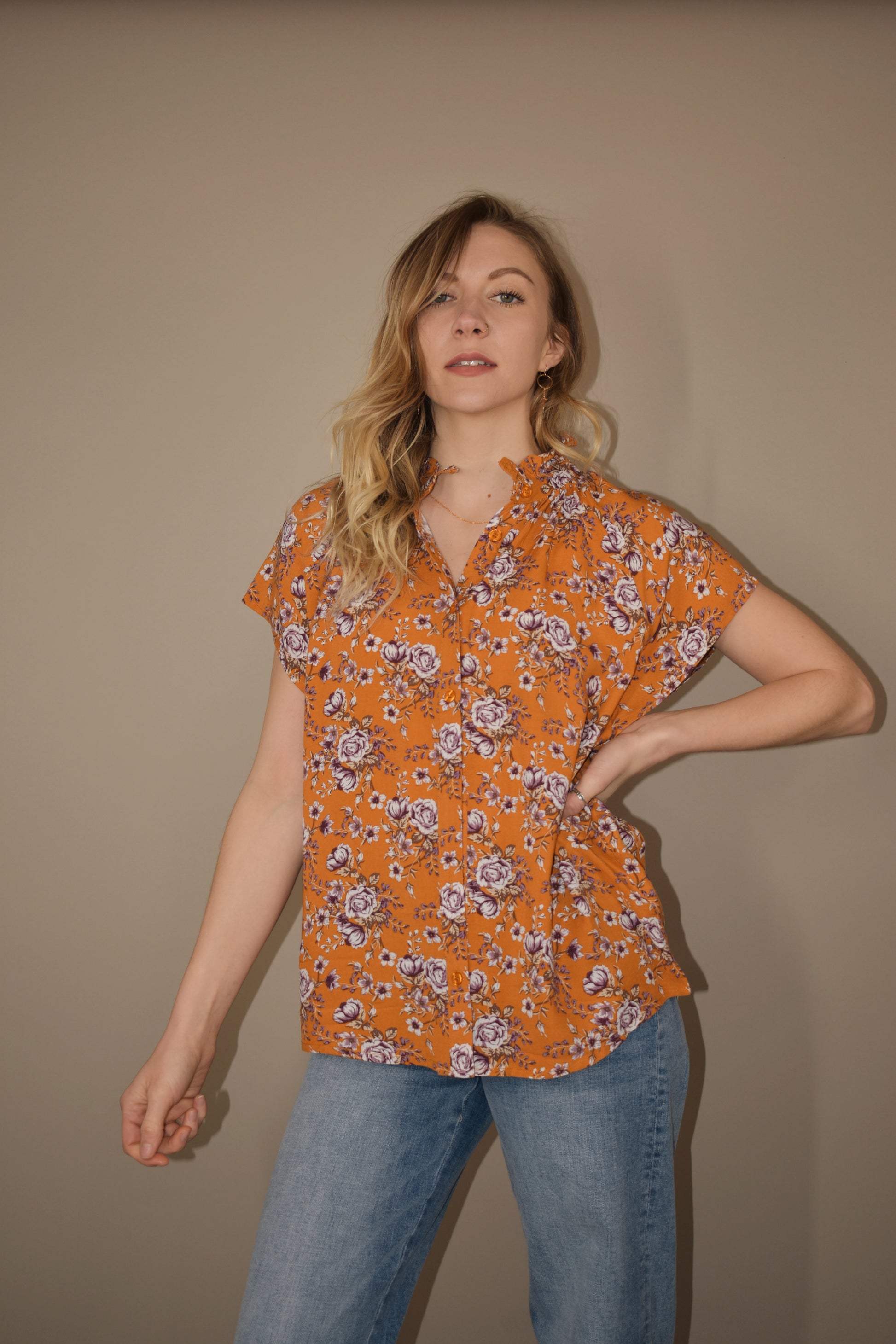 tangerine button down relaxed fit blouse with white and purple floral pattern. ruffle collar. flutter cap sleeves. full length