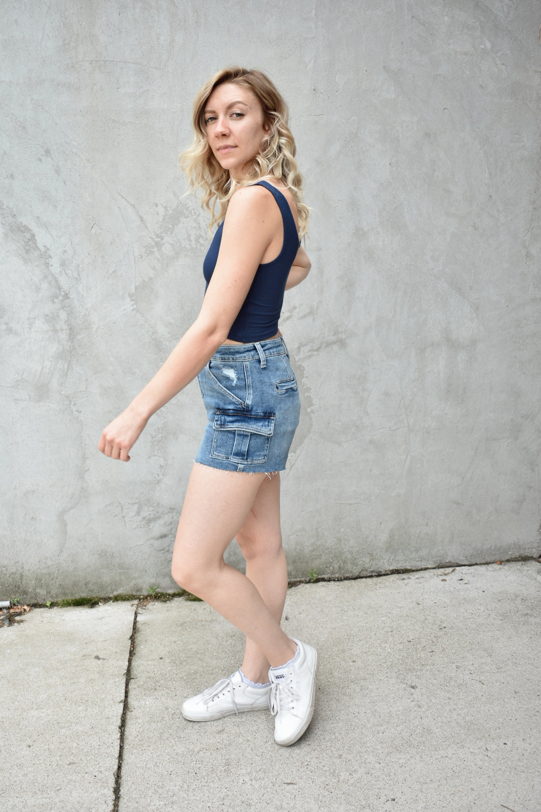denim high rise medium wash cargo shorts with small cargo style pockets on the side. Stretch denim. The brand is Vervet
