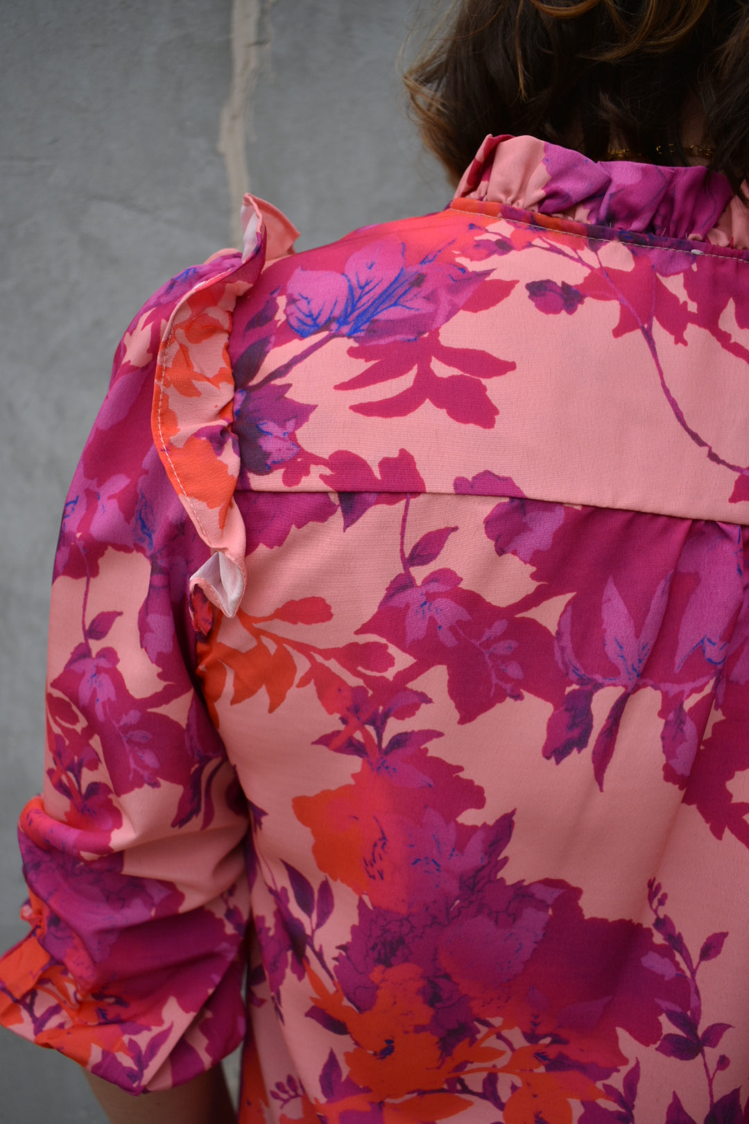 fuchsia, orange, light purple, and blush patterned button down blouse. ruffled V-neckline and ruffled shoulder detailing. Button-cuffed 3/4 sleeves. The brand is First Love.