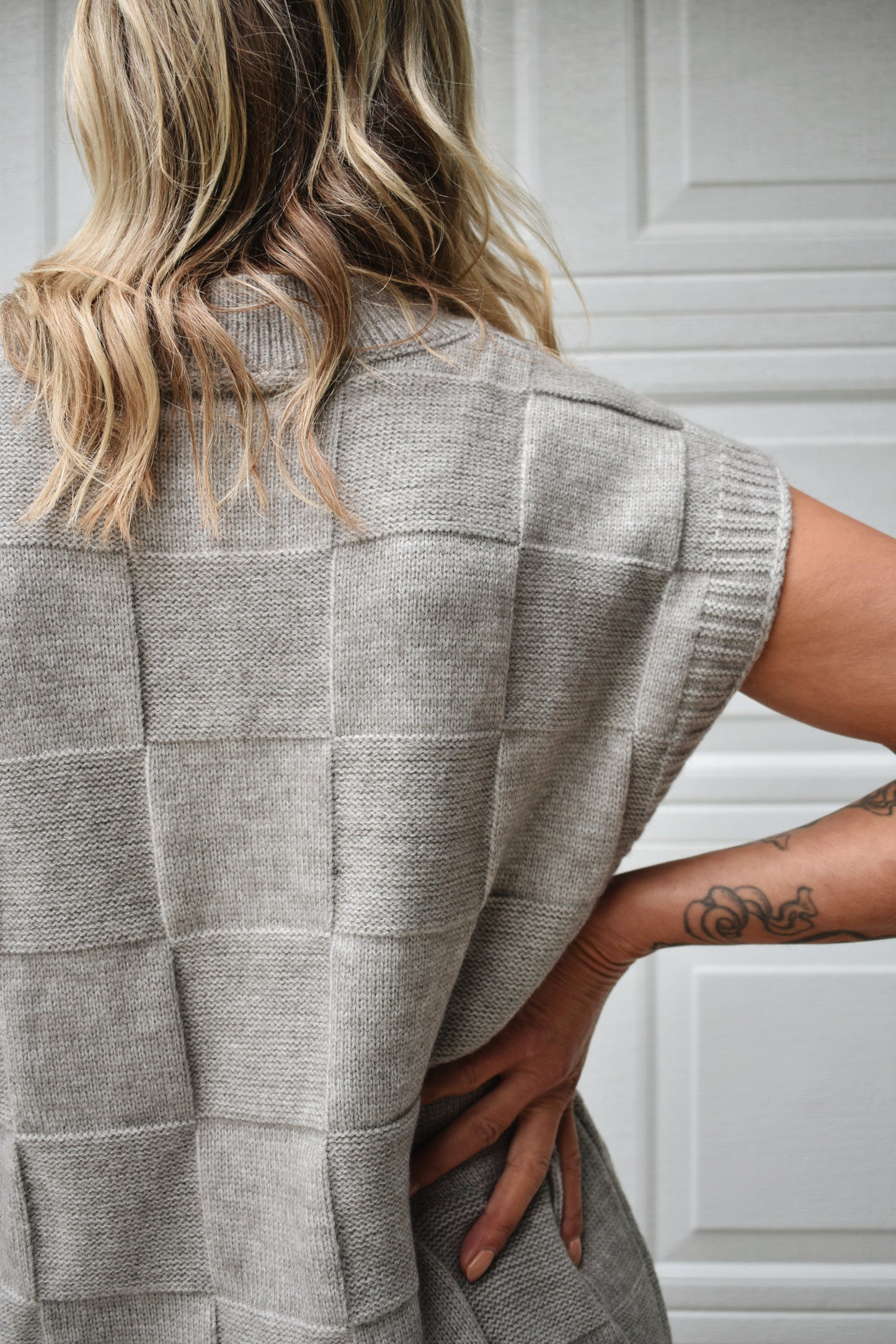 Light grey sweater vest with knit basket weave fabric and ribbed neckline, shoulders, and hem. V-neckline and waist-length cut