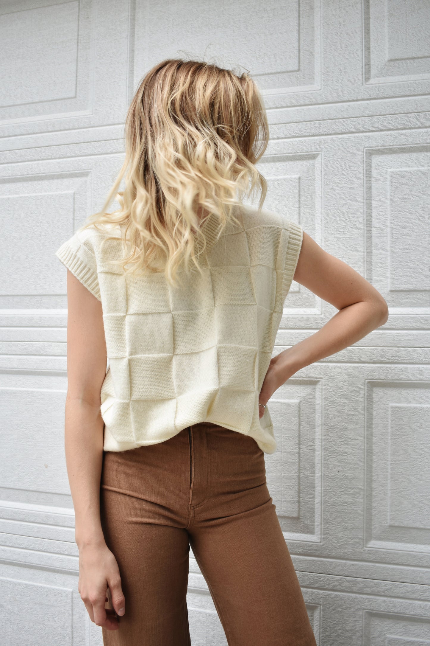 cream sweater vest with knit basket weave fabric and ribbed neckline, shoulders, and hem. V-neckline and waist-length cut