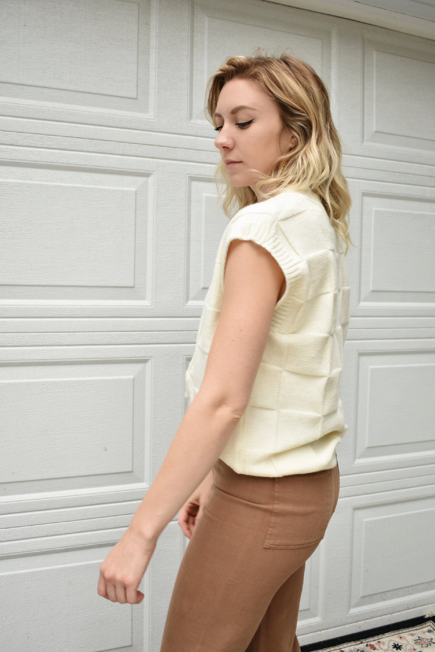 cream sweater vest with knit basket weave fabric and ribbed neckline, shoulders, and hem. V-neckline and waist-length cut
