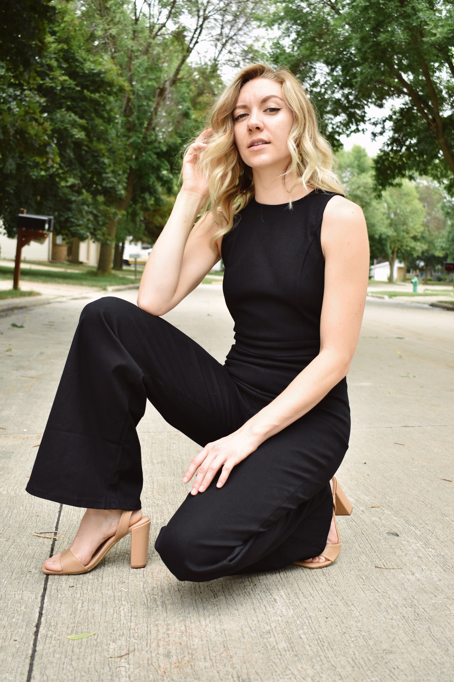 Black denim sleeveless jumpsuit with flared legs and high neck