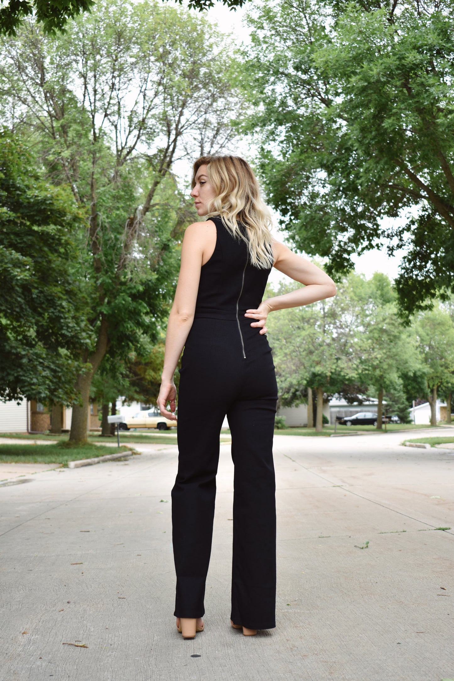 Black denim sleeveless jumpsuit with flared legs and high neck