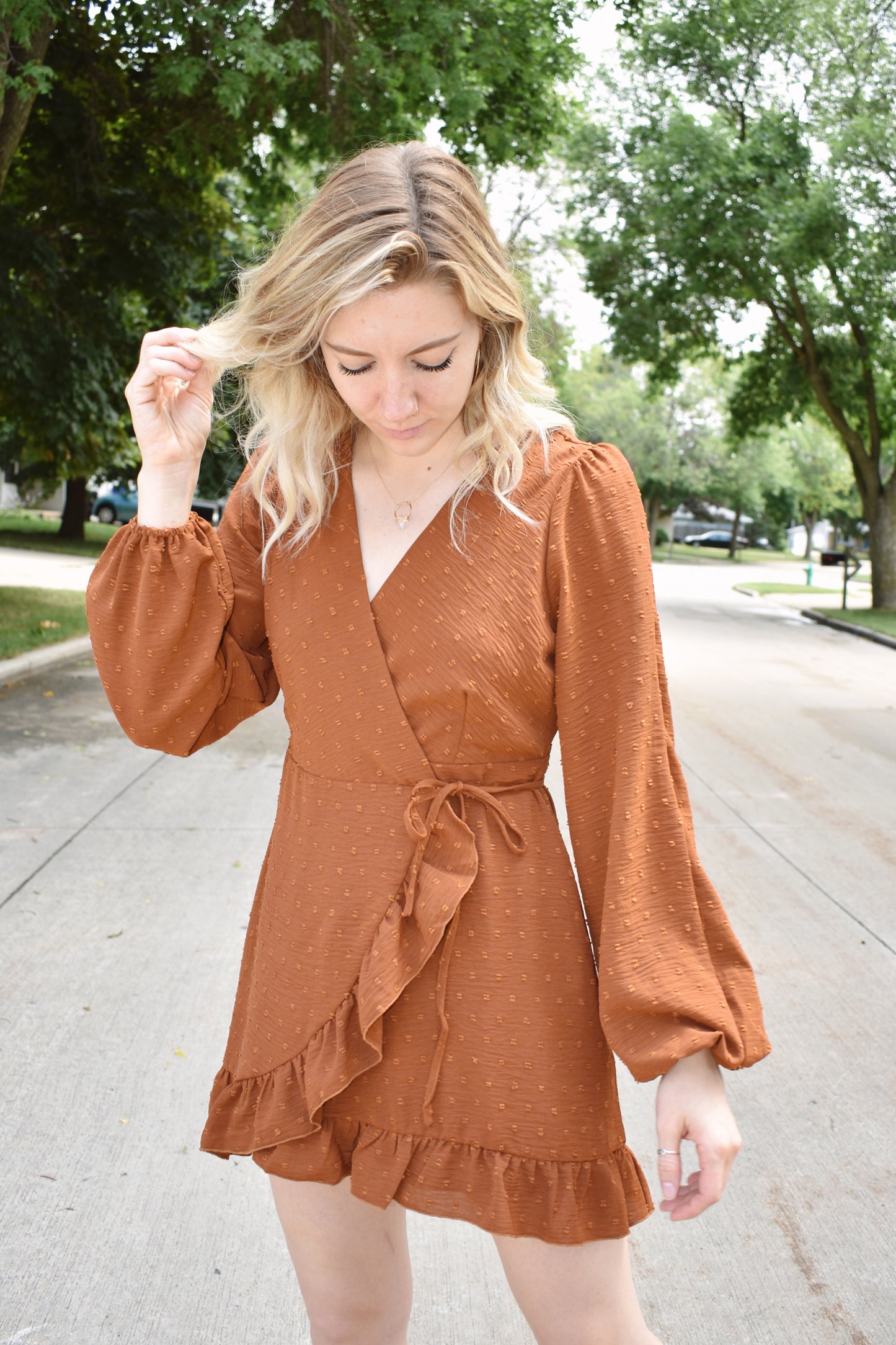 Rust swiss dot textured mini wrap dress with long billow sleeves and ruffled hem