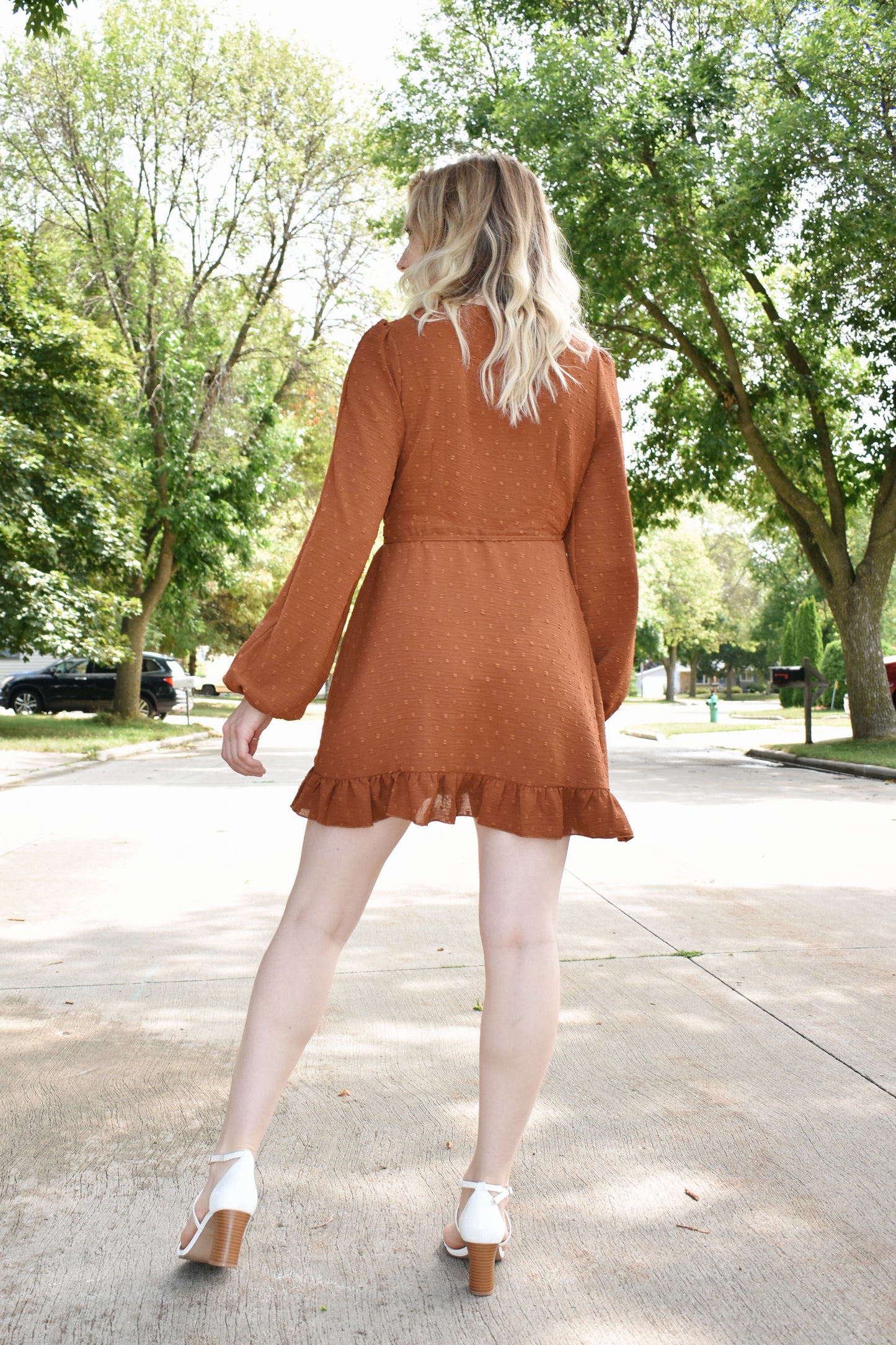 Rust swiss dot textured mini wrap dress with long billow sleeves and ruffled hem