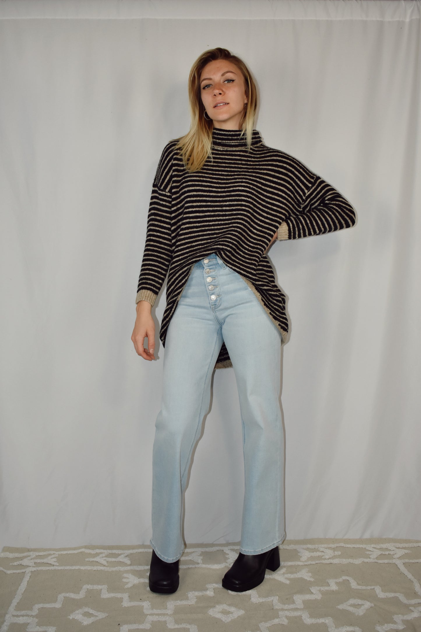 Pullover turtleneck striped sweater. Drop shoulder long sleeves, ribbed hem and sleeve cuffs, and high-low rounded hem. Black and taupe color.
