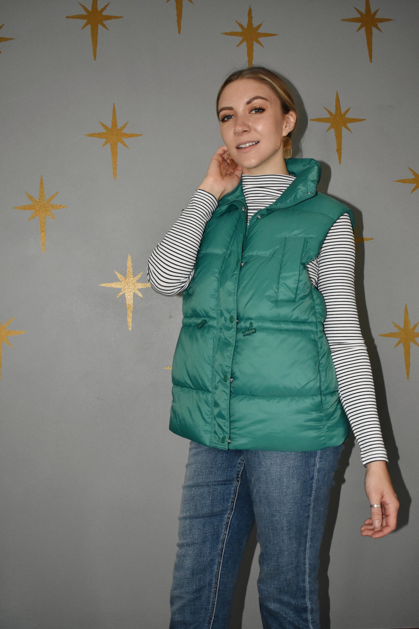 Lightweight zip up puffer vest with sinch drawstring around waist for adjustable fit. 4 pockets. green.