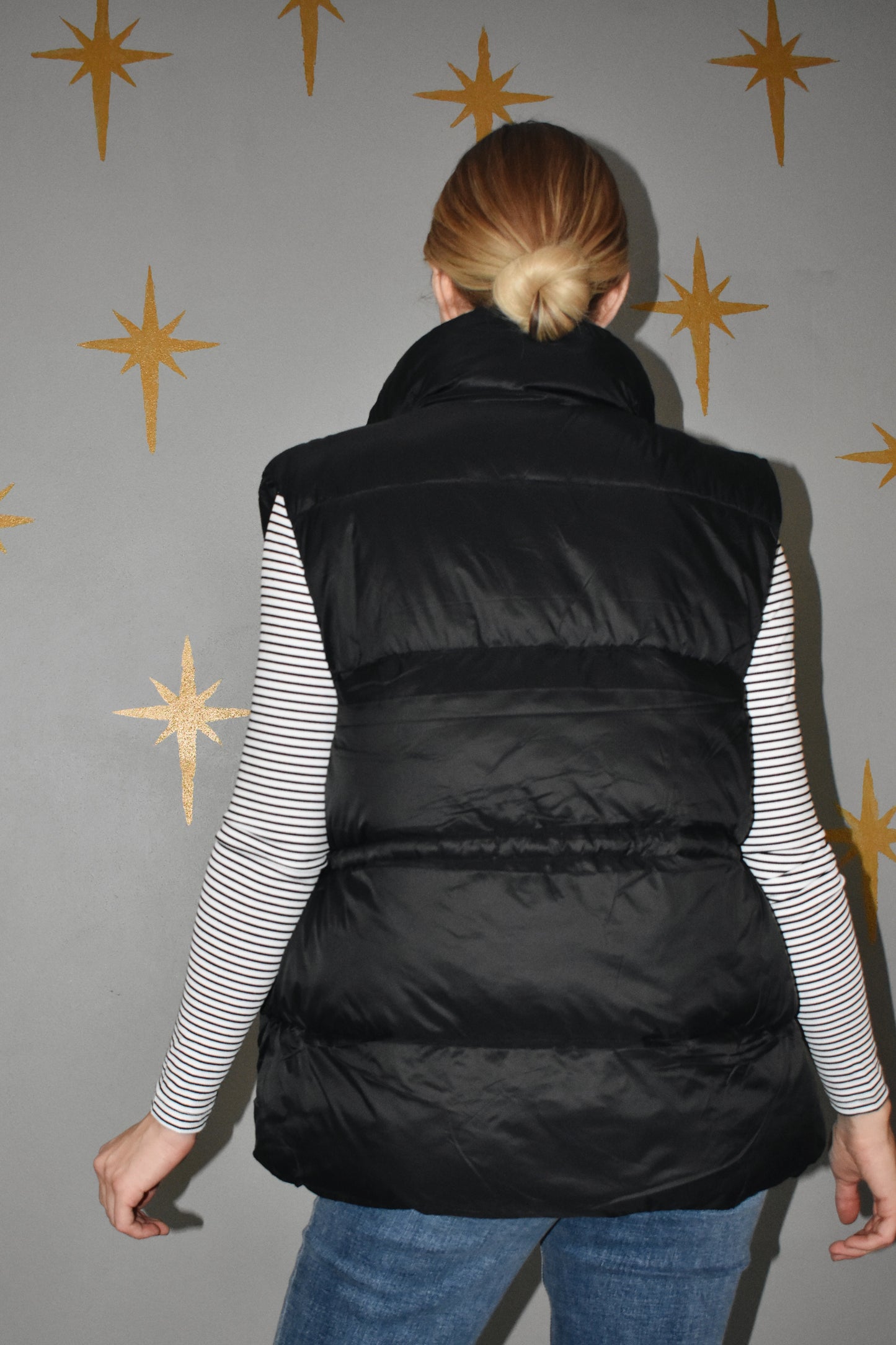Lightweight zip up puffer vest with sinch drawstring around waist for adjustable fit. 4 pockets. Black.