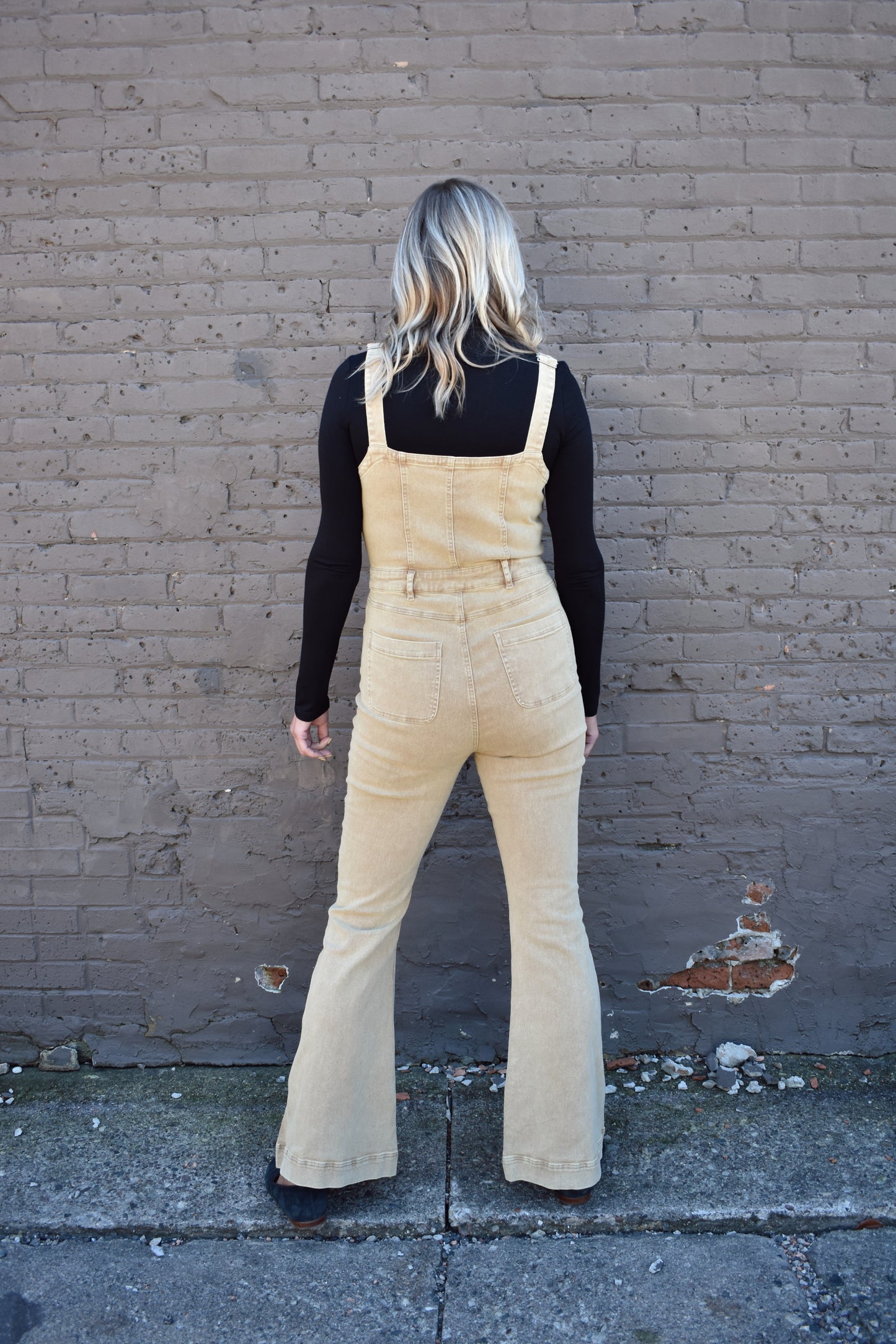tan fitted denim overalls with bell bottoms and buttons down the front. waistline band has beltloops and front and back pockets. Adjustable straps.