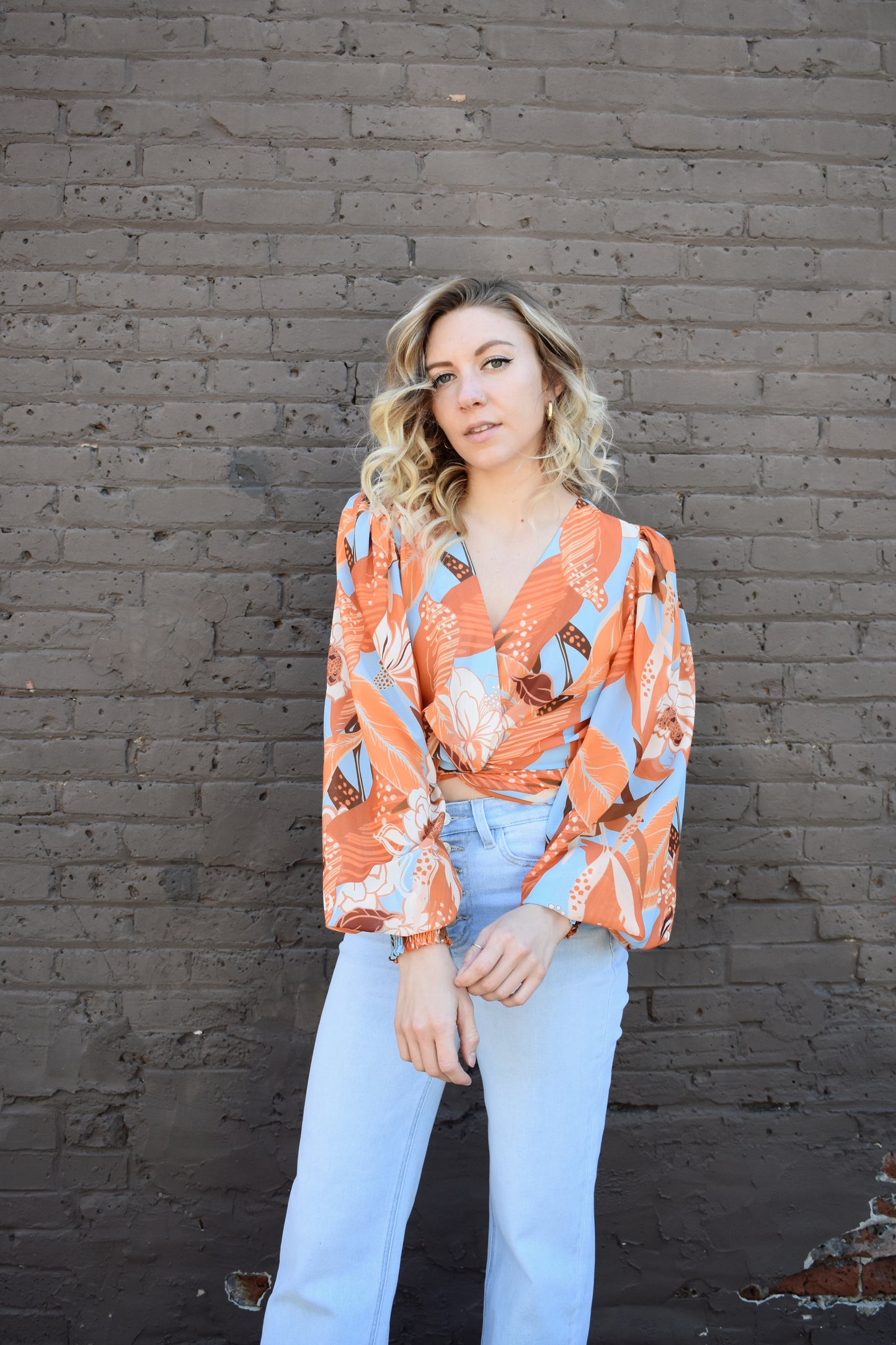 light blue and shades of orange printed lightweight long sleeve v neck line top with twist detail in front and smocked cuffs with balloon sleeves. smocked back waistband.