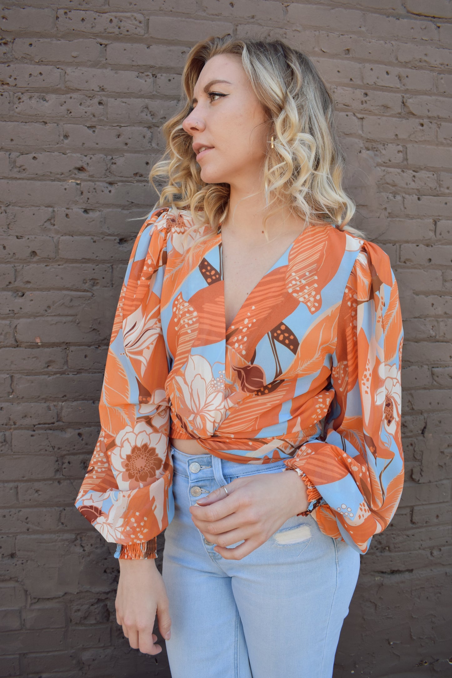 light blue and shades of orange printed lightweight long sleeve v neck line top with twist detail in front and smocked cuffs with balloon sleeves. smocked back waistband.