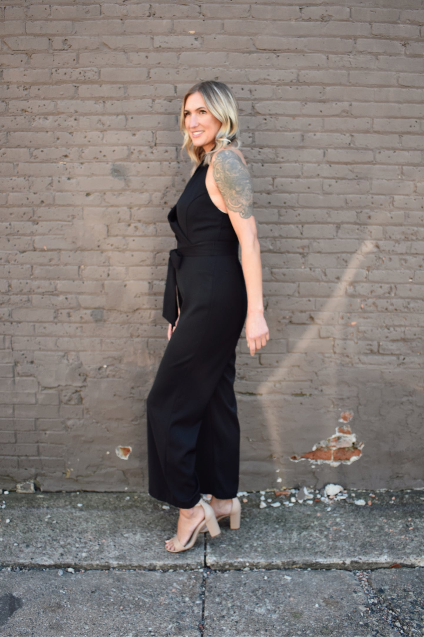 Black formal jumpsuit. Surplice neckline with lapels. Halter with button enclosure. tie waist. straight leg.