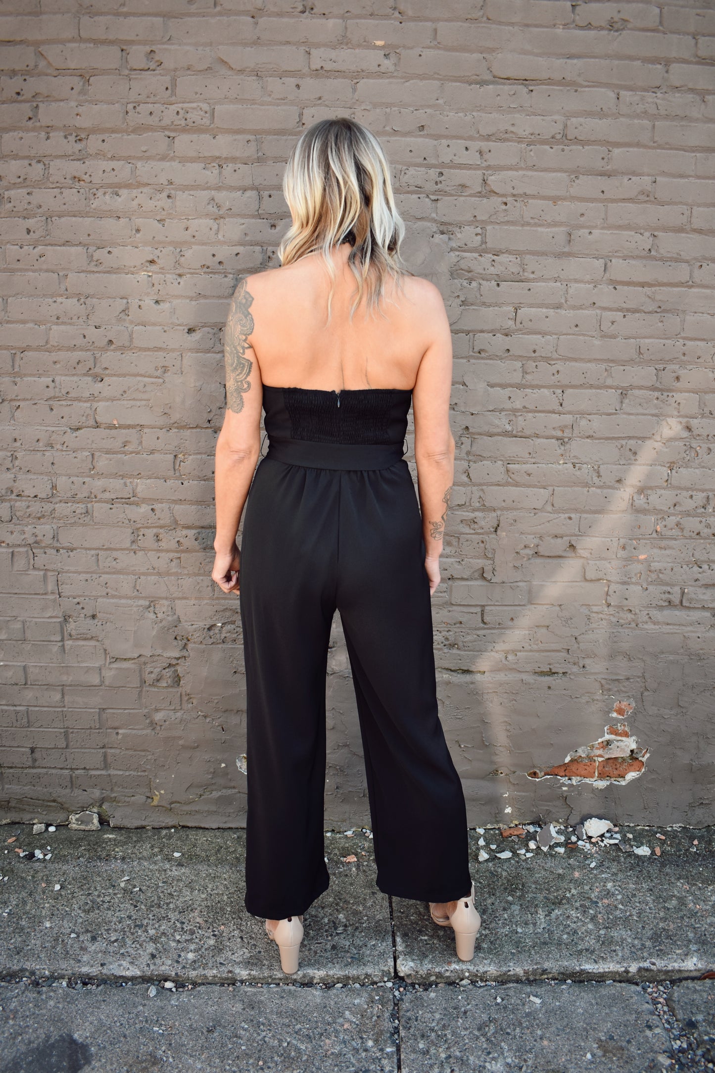 Black formal jumpsuit. Surplice neckline with lapels. Halter with button enclosure. tie waist. straight leg.