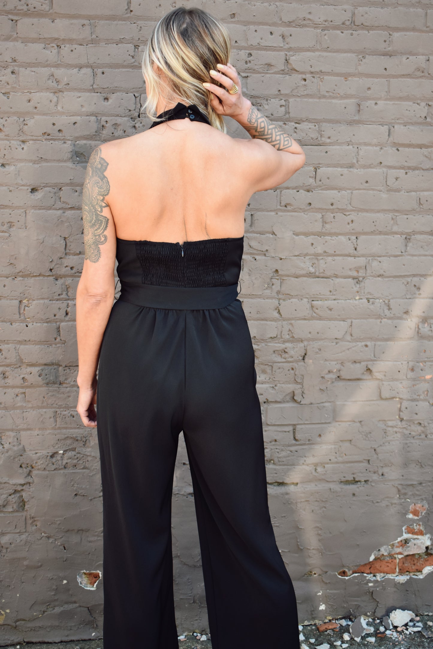 Black formal jumpsuit. Surplice neckline with lapels. Halter with button enclosure. tie waist. straight leg.