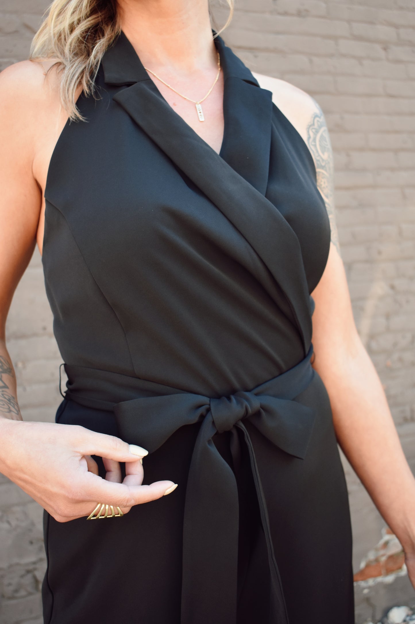 Black formal jumpsuit. Surplice neckline with lapels. Halter with button enclosure. tie waist. straight leg.