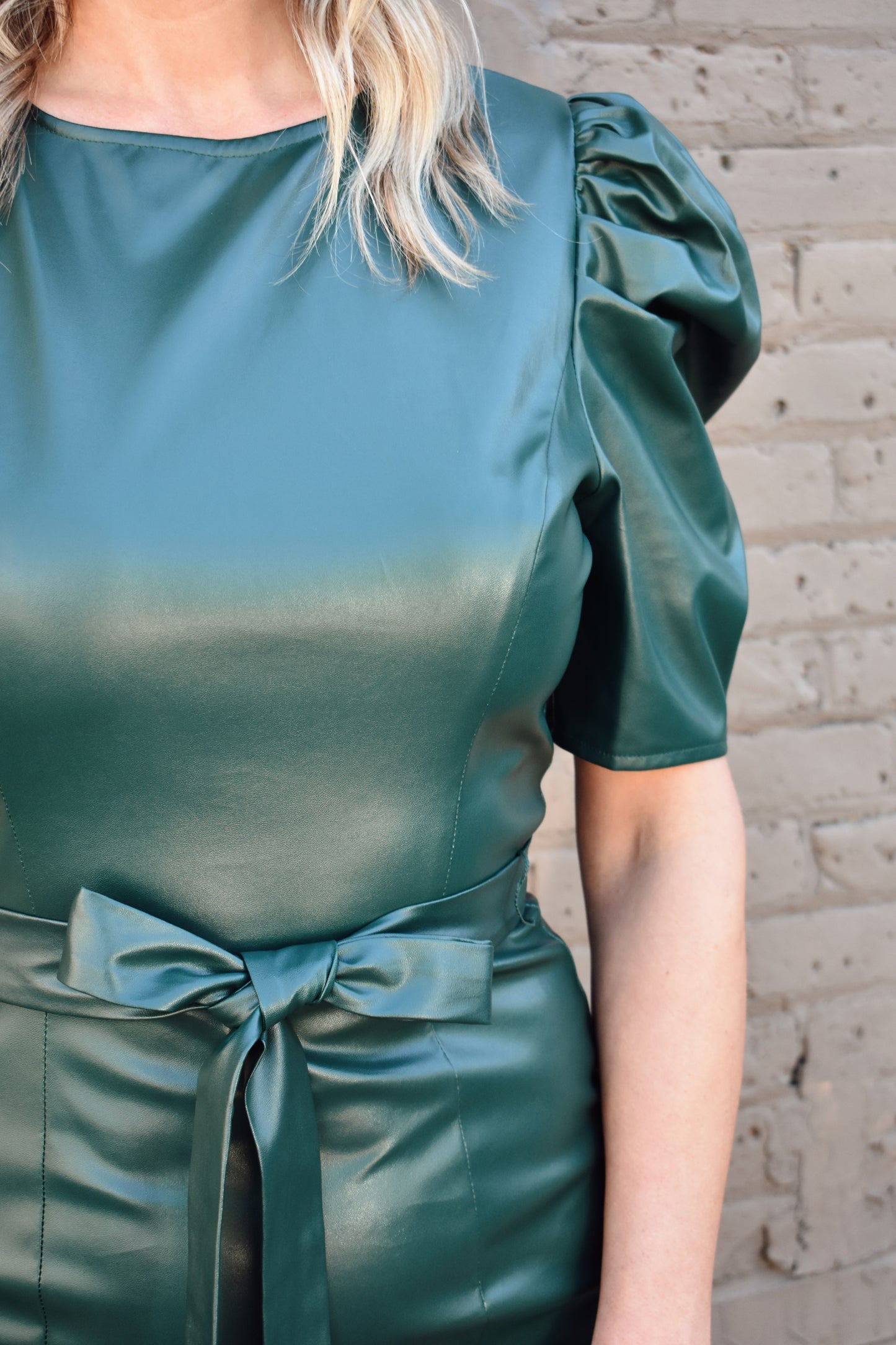 bold dark green faux leather midi dress fitted with slight flare at bottom. Short puff sleeves, crew neck, self tie waist, zipper enclosure