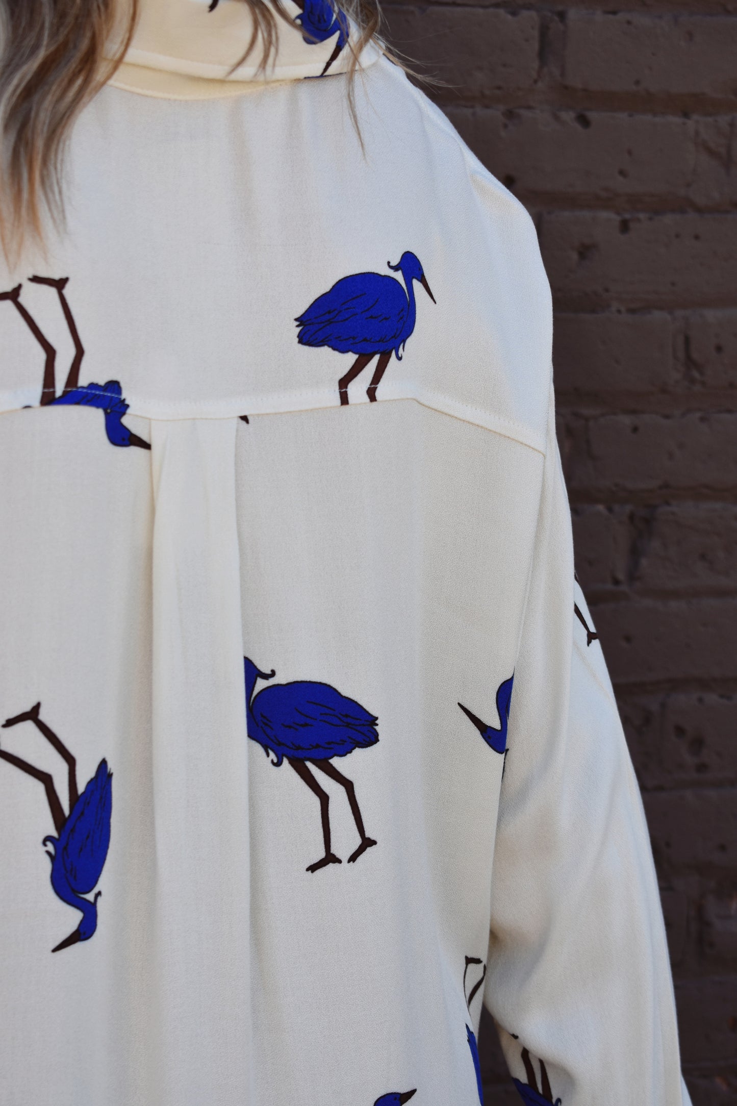 White relaxed fit button down with blue birds printed on it. High low hem. Drop shoulders.