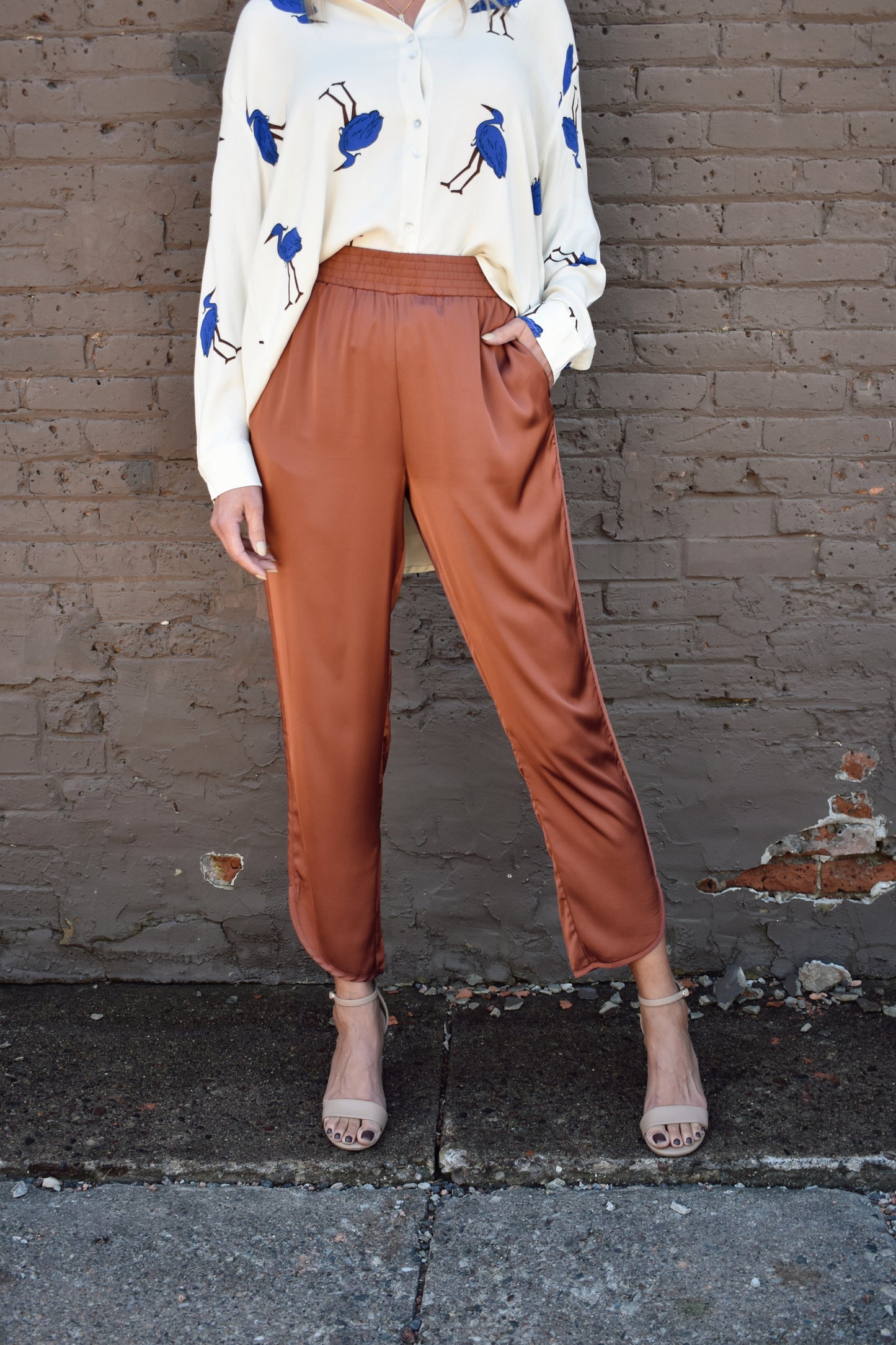 Copper colored satin joggers with side pockets and elastic waistband. rounded tulip hem with welted side seams.