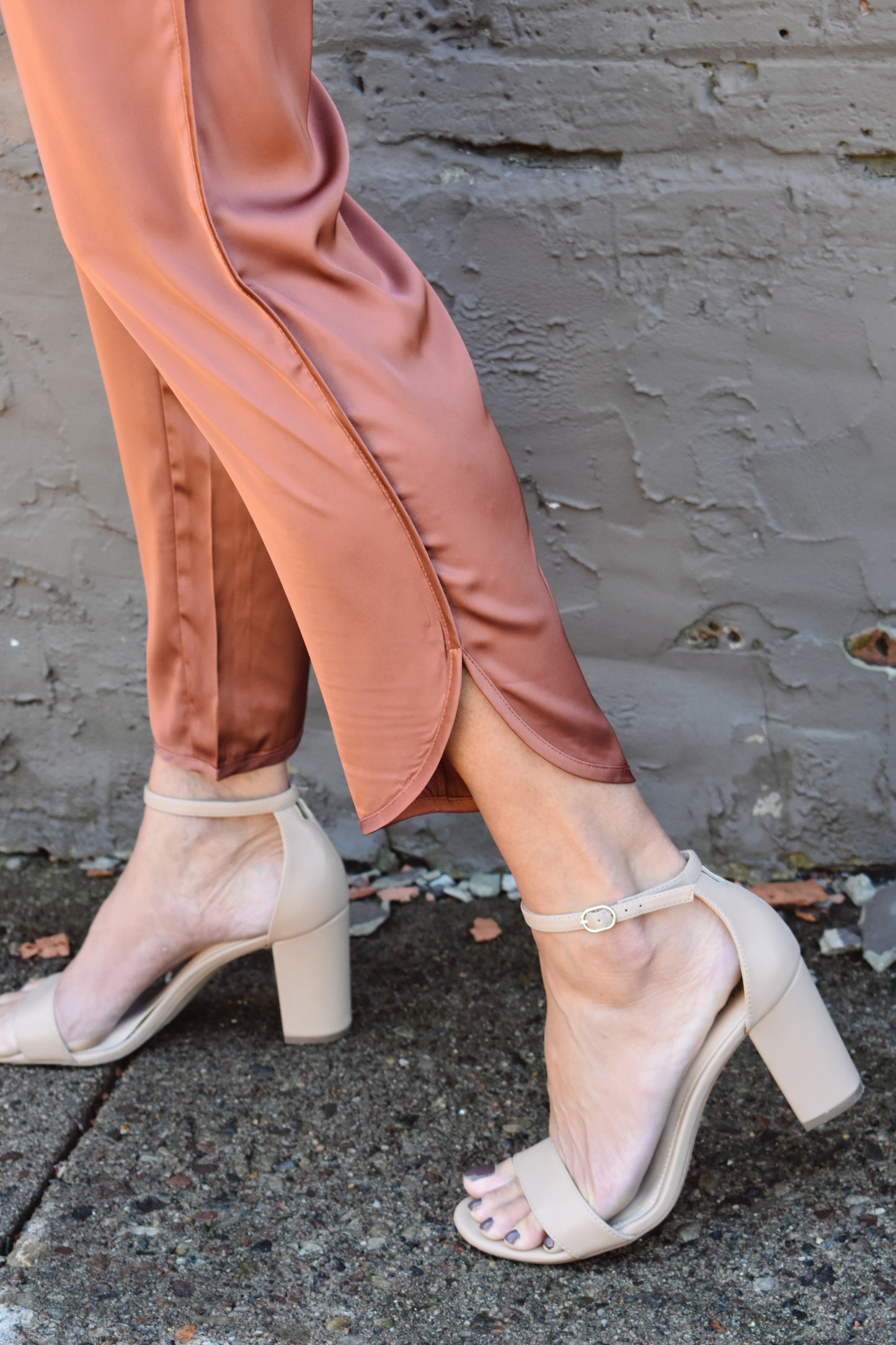 Copper colored satin joggers with side pockets and elastic waistband. rounded tulip hem with welted side seams.