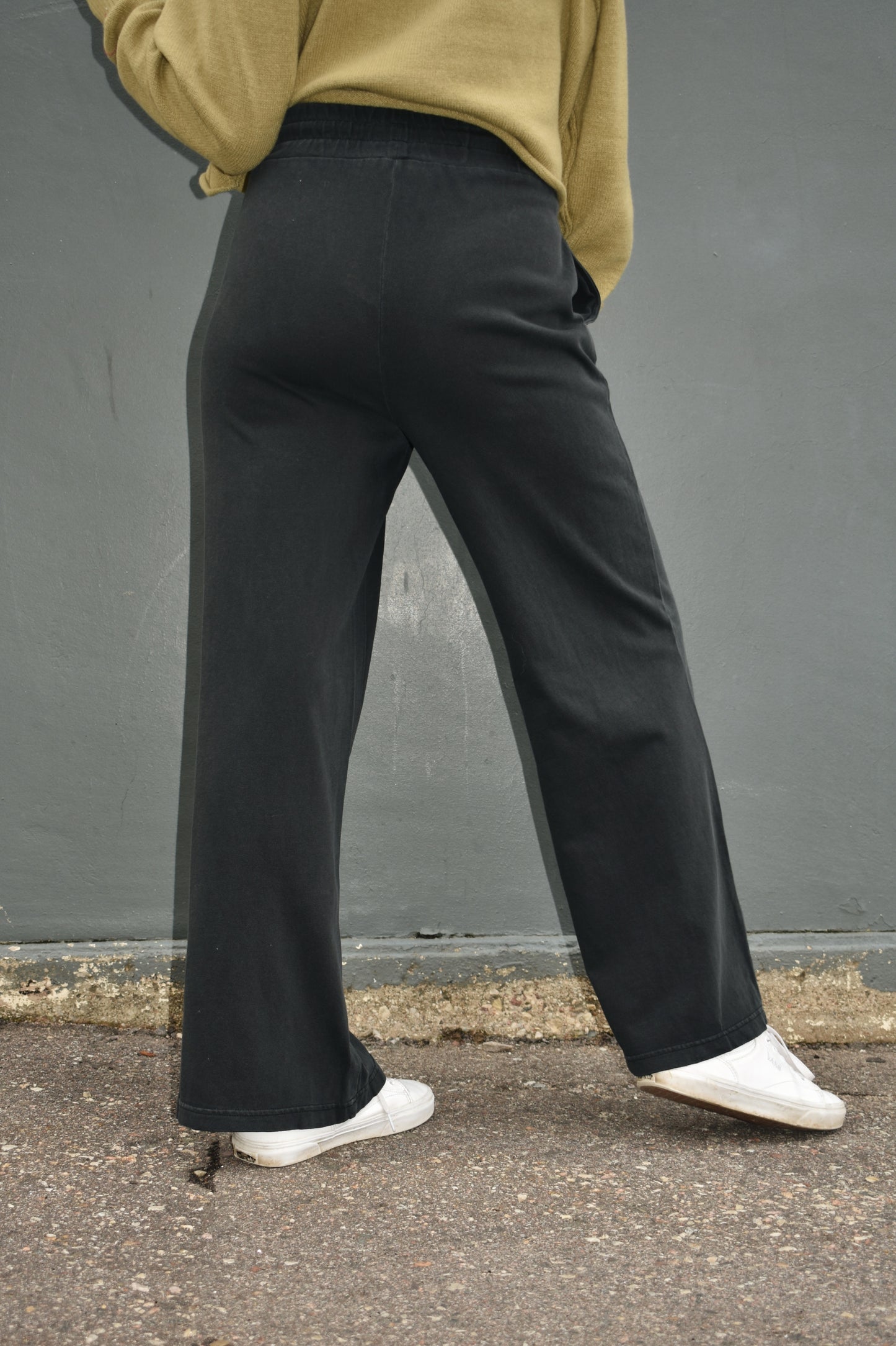 black wide leg athleisure pants with elastic waistband with drawstring, pockets and seam detail down the front of the legs.