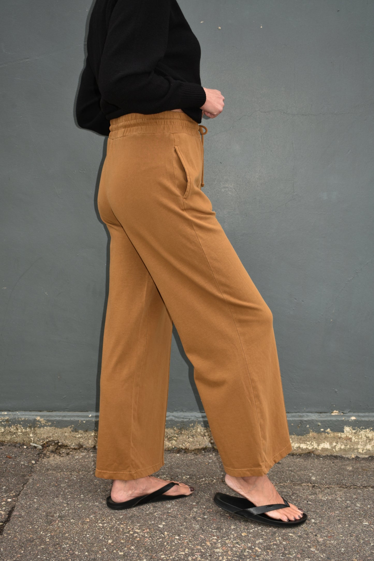 pale brown wide leg athleisure pants with elastic waistband with drawstring, pockets and seam detail down the front of the legs.