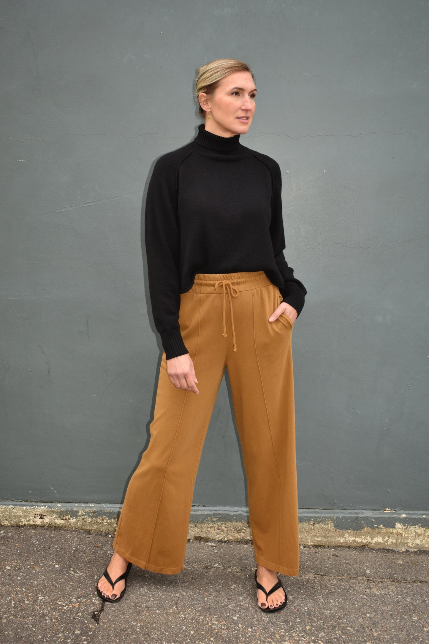 pale brown wide leg athleisure pants with elastic waistband with drawstring, pockets and seam detail down the front of the legs.