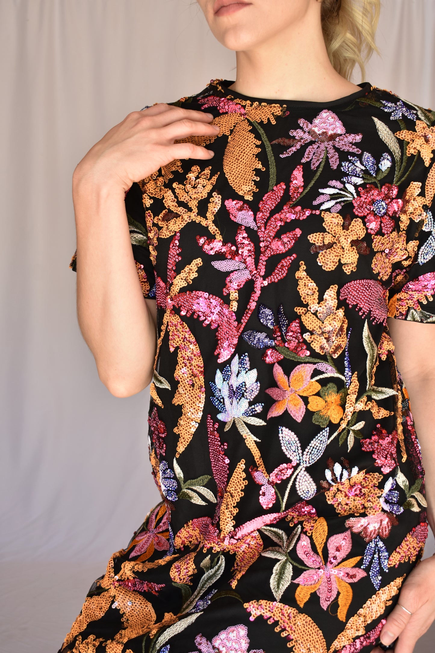 sequin short sleeve mini dress. black background with multi colored sequin floral design completely covering dress. pink, orange, lilac, light blue colors. crew neck. single button enclosure at the back of neck. no zipper. lined.