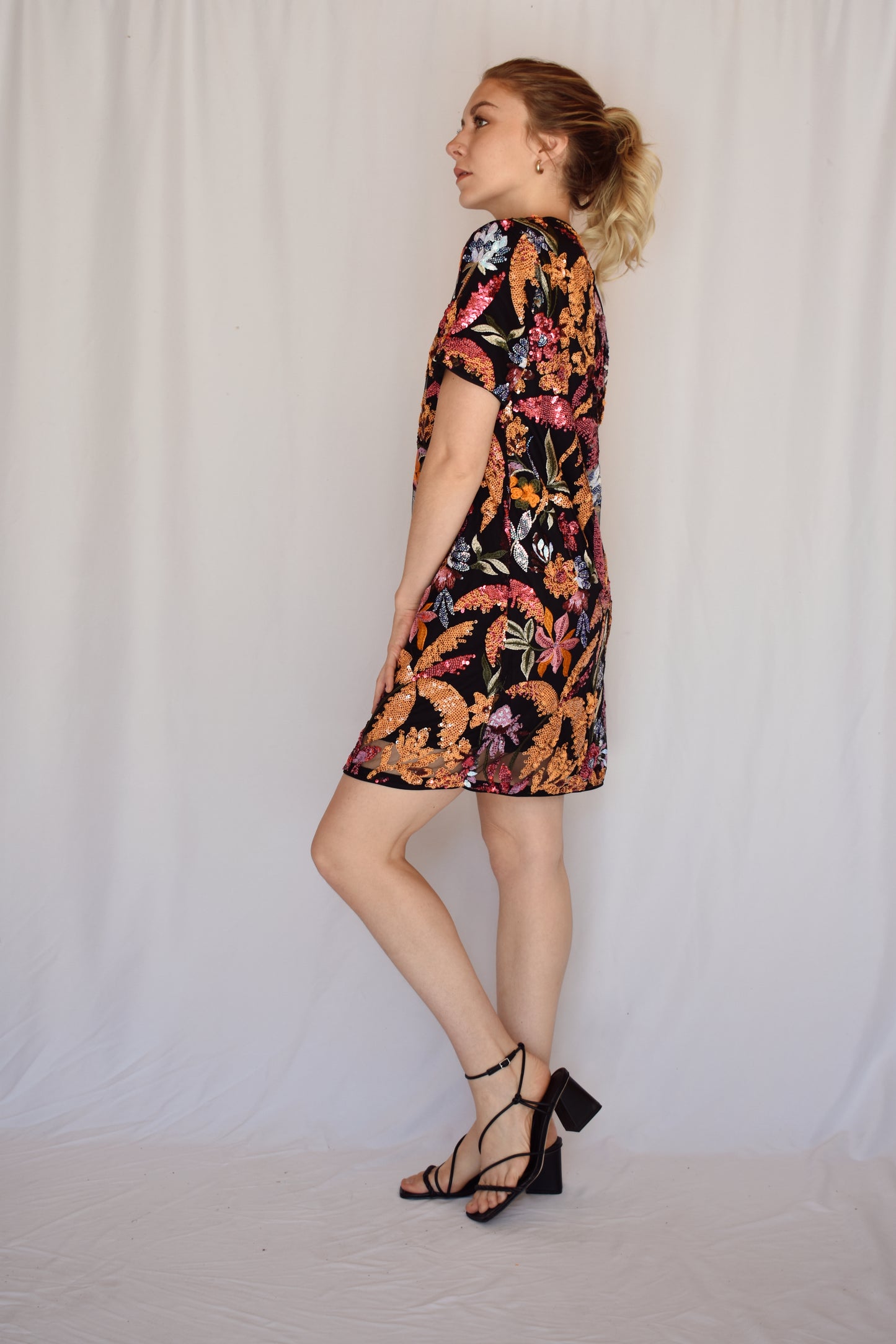 sequin short sleeve mini dress. black background with multi colored sequin floral design completely covering dress. pink, orange, lilac, light blue colors. crew neck. single button enclosure at the back of neck. no zipper. lined.