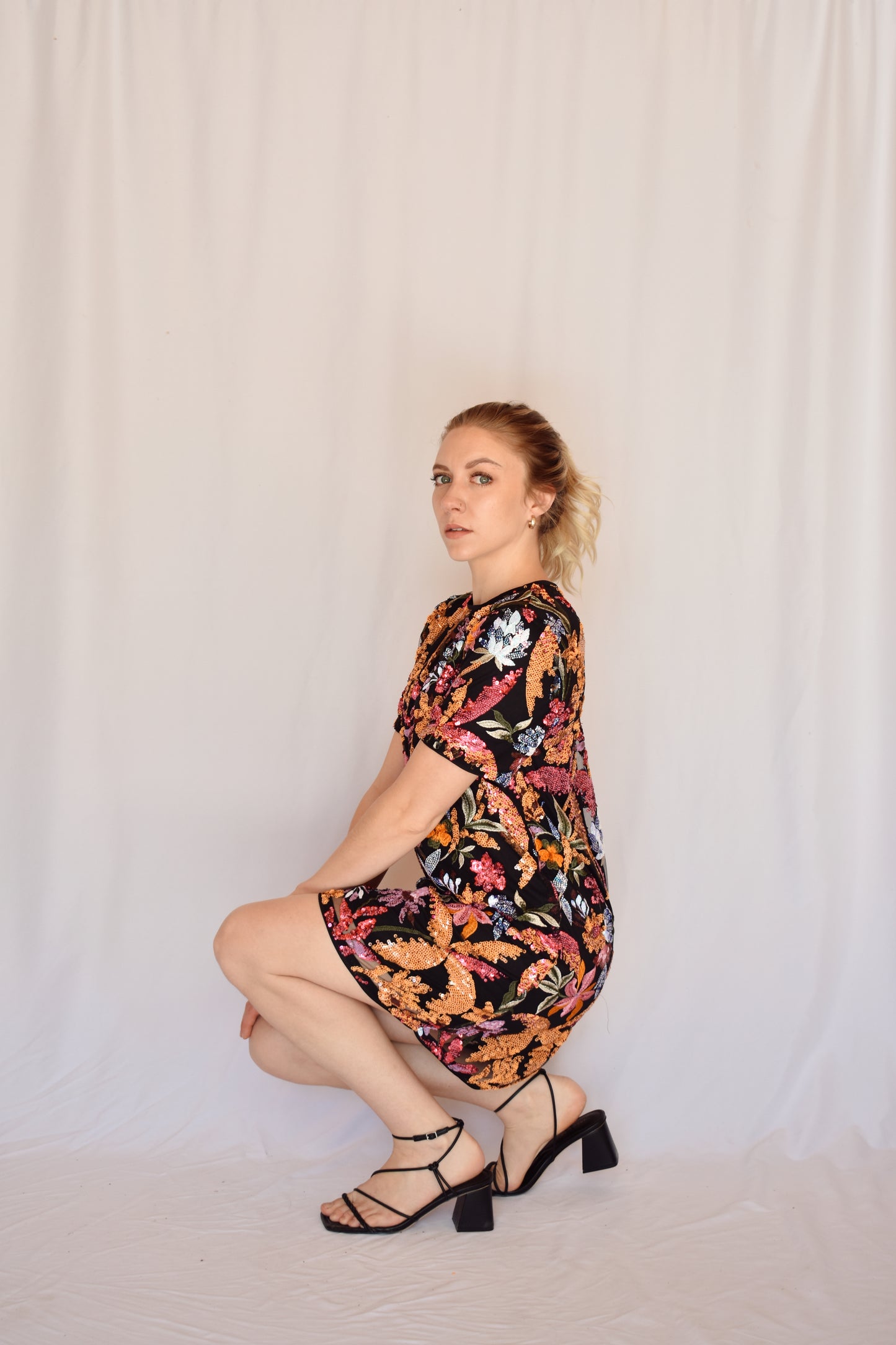 sequin short sleeve mini dress. black background with multi colored sequin floral design completely covering dress. pink, orange, lilac, light blue colors. crew neck. single button enclosure at the back of neck. no zipper. lined.