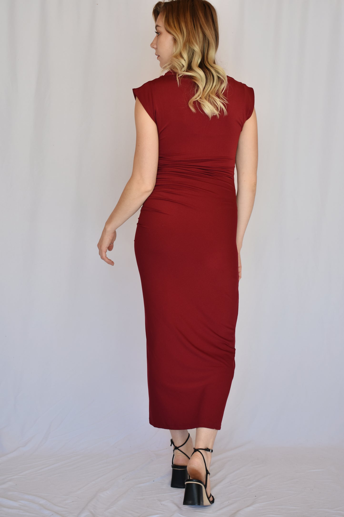 burgundy midi dress. form fitting with slit up left side with rushing detail on the side of the bodice. cap sleeves with mock neck and draping detail in fabric across chest. Stretch fabric.