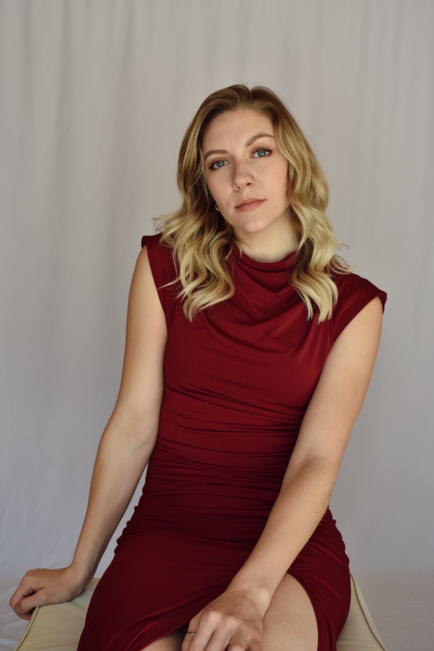 burgundy midi dress. form fitting with slit up left side with rushing detail on the side of the bodice. cap sleeves with mock neck and draping detail in fabric across chest. Stretch fabric.
