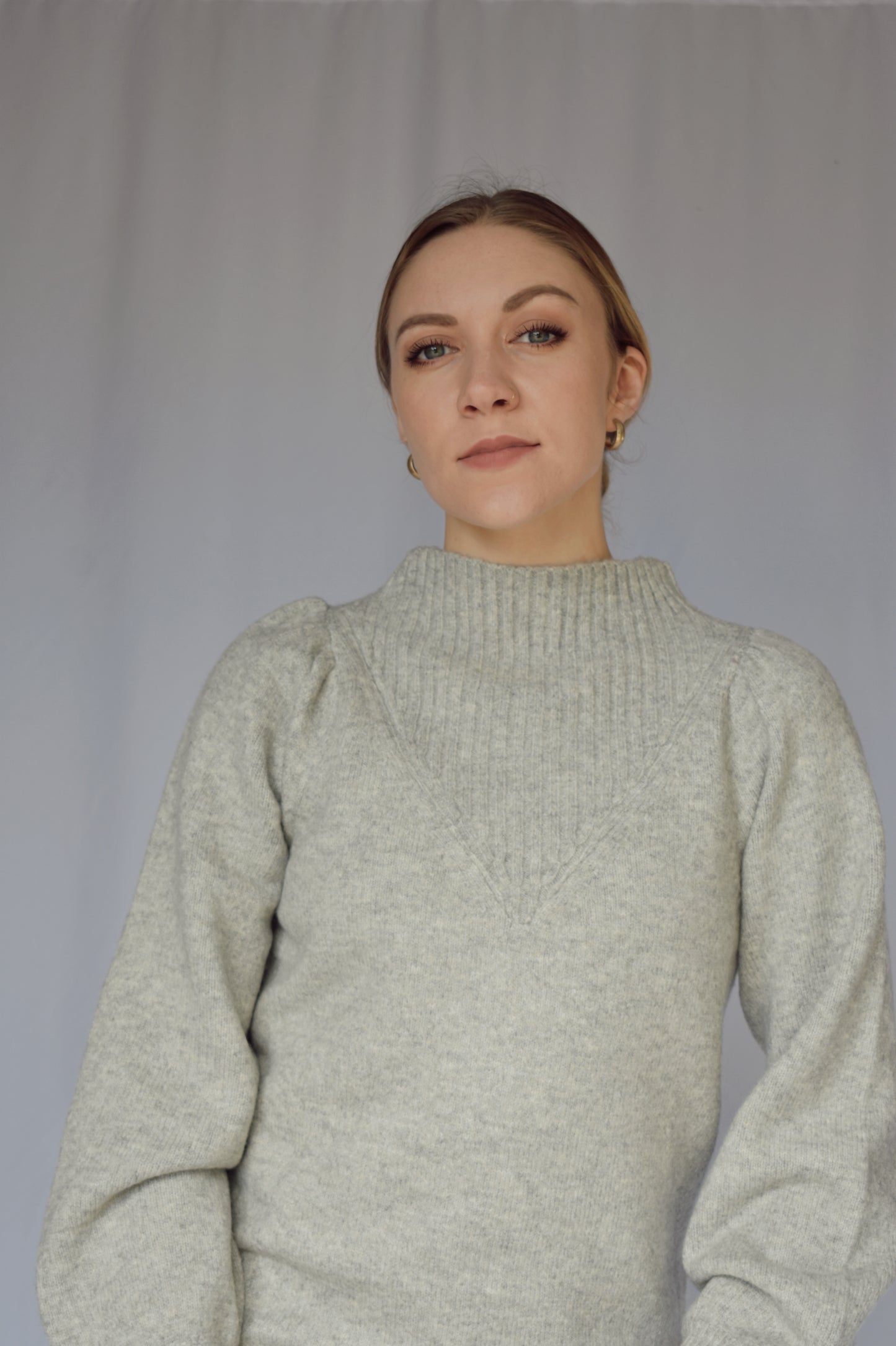 heather gray sweater dress with long sleeves. ribbed cuffs and mock neck with v neck ribbed detail. slight puff on shoulders. hits just above the knees. relaxed fit, not oversized.