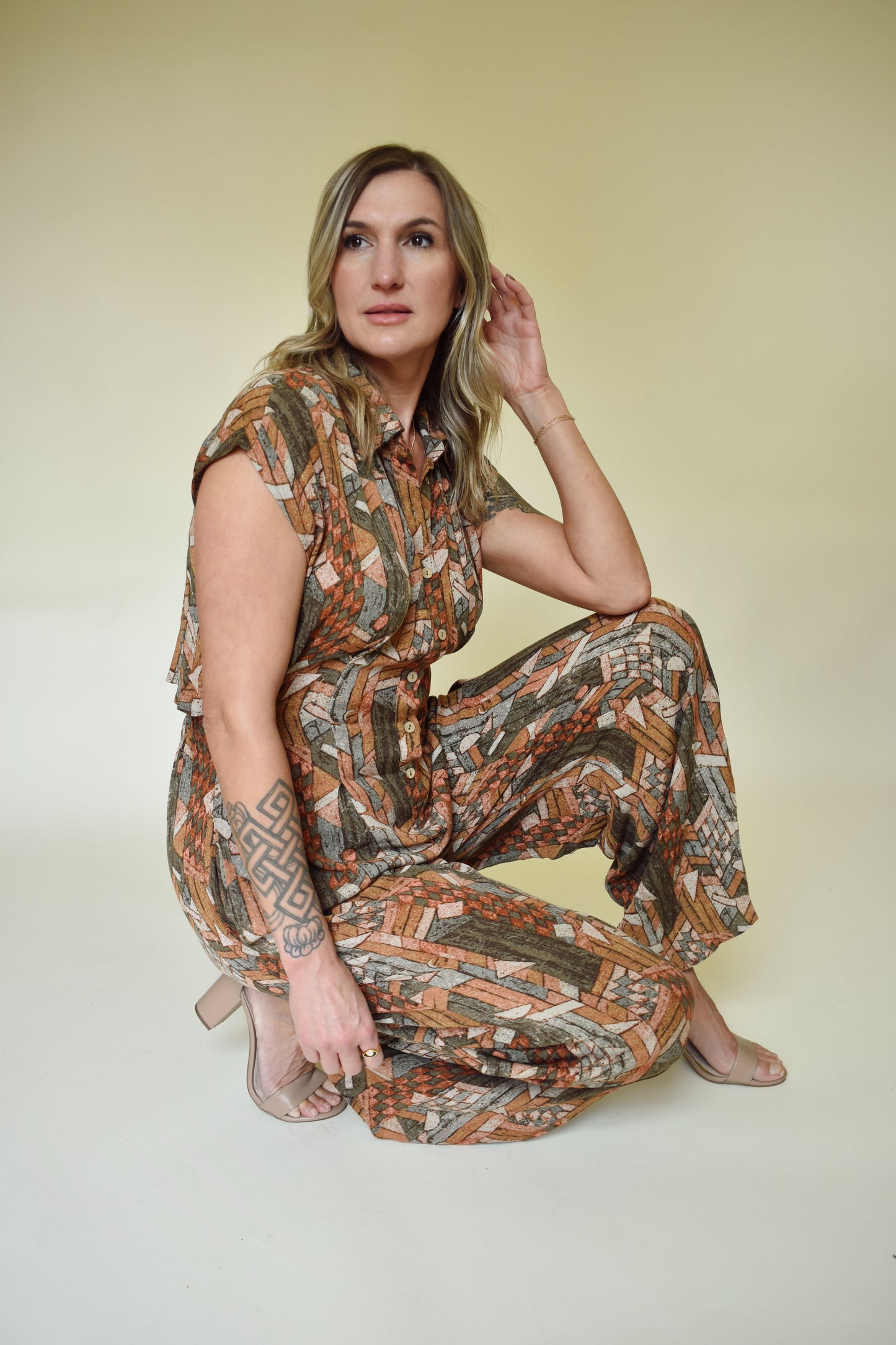 neutral/earth tone boho patterned jumpsuit with cap sleeves and collar with front button down. wide leg, synching in back with horizontal split on lower back so theres an open back effect but not revealing.