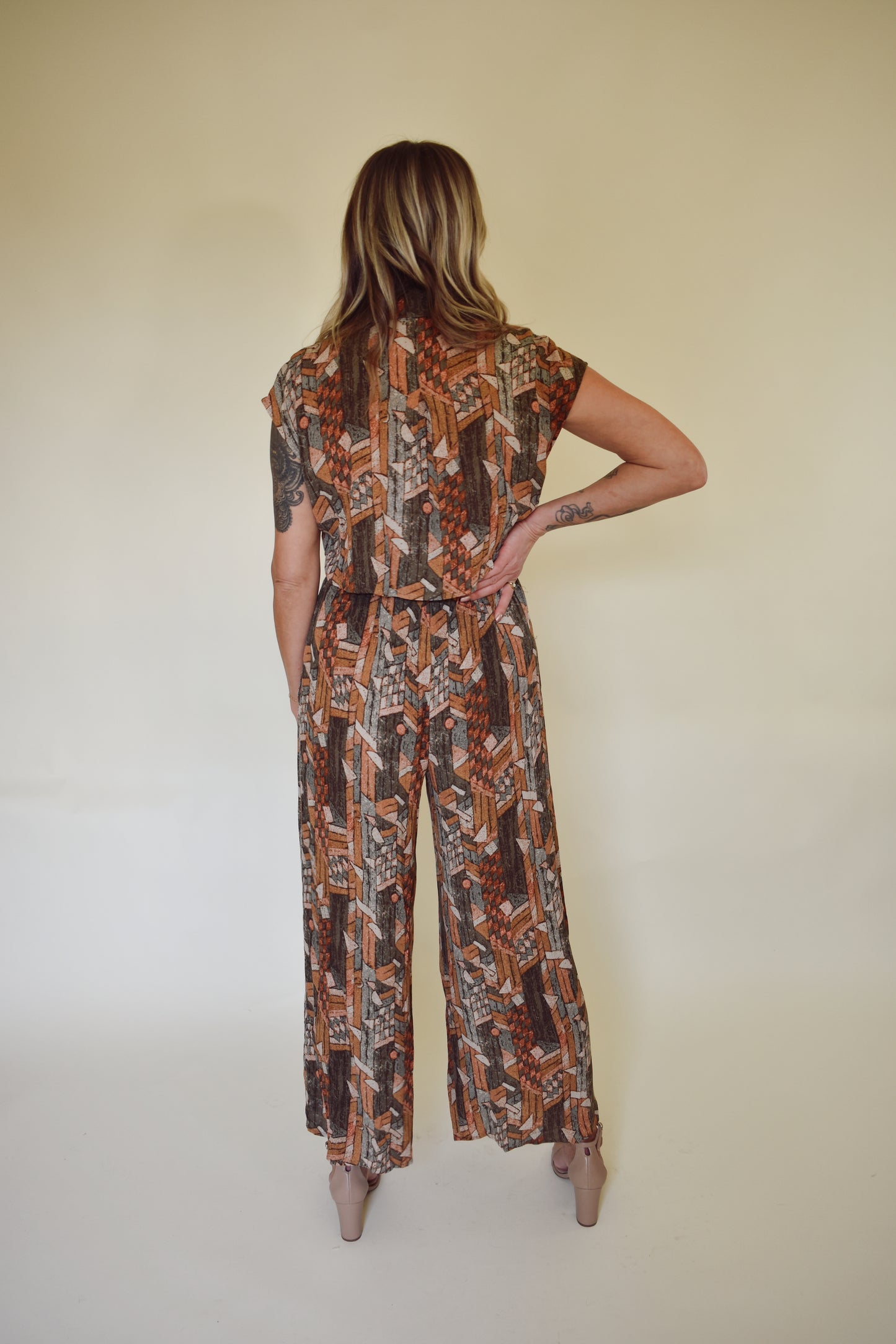 neutral/earth tone boho patterned jumpsuit with cap sleeves and collar with front button down. wide leg, synching in back with horizontal split on lower back so theres an open back effect but not revealing.