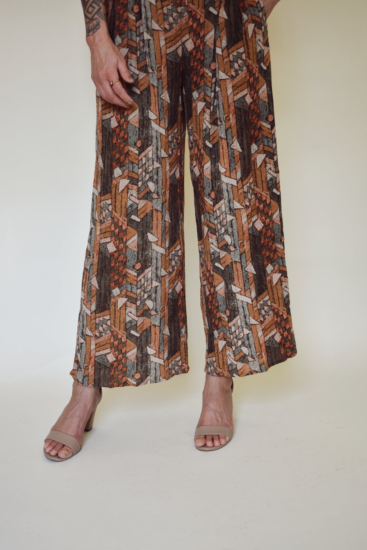 neutral/earth tone boho patterned jumpsuit with cap sleeves and collar with front button down. wide leg, synching in back with horizontal split on lower back so theres an open back effect but not revealing.