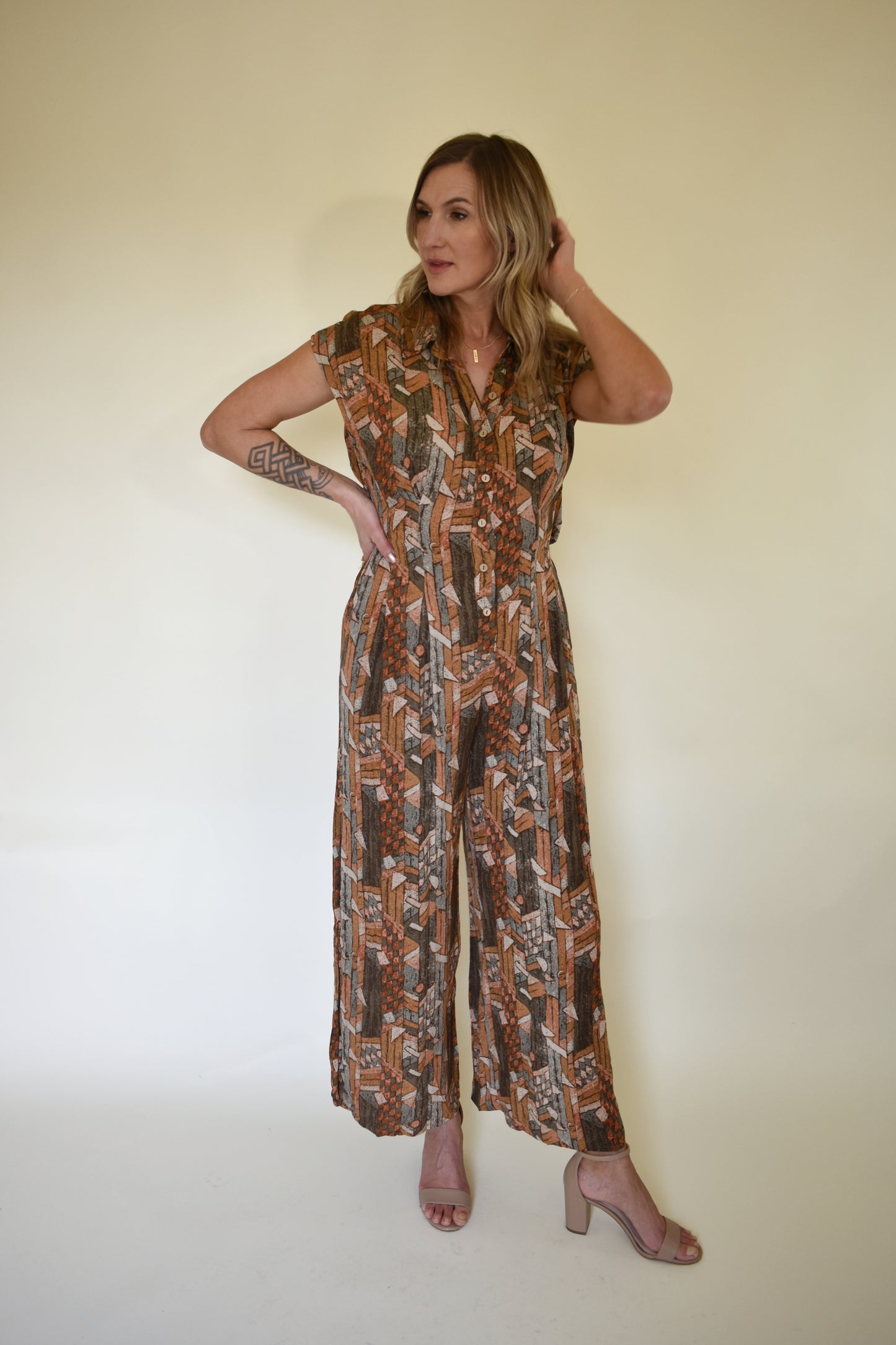 neutral/earth tone boho patterned jumpsuit with cap sleeves and collar with front button down. wide leg, synching in back with horizontal split on lower back so theres an open back effect but not revealing.